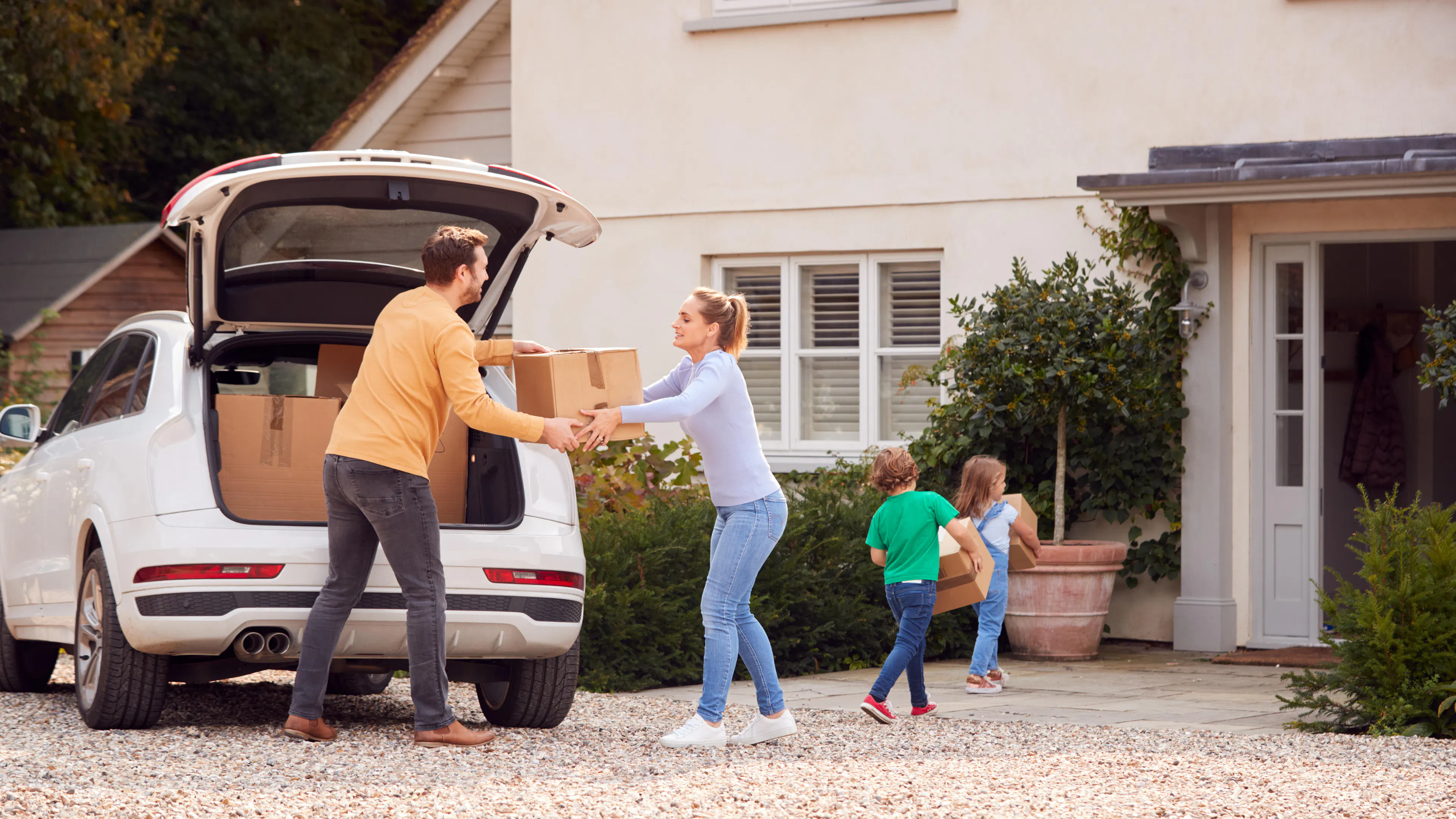 Eine Familie lädt Umzugskisten ins Auto.