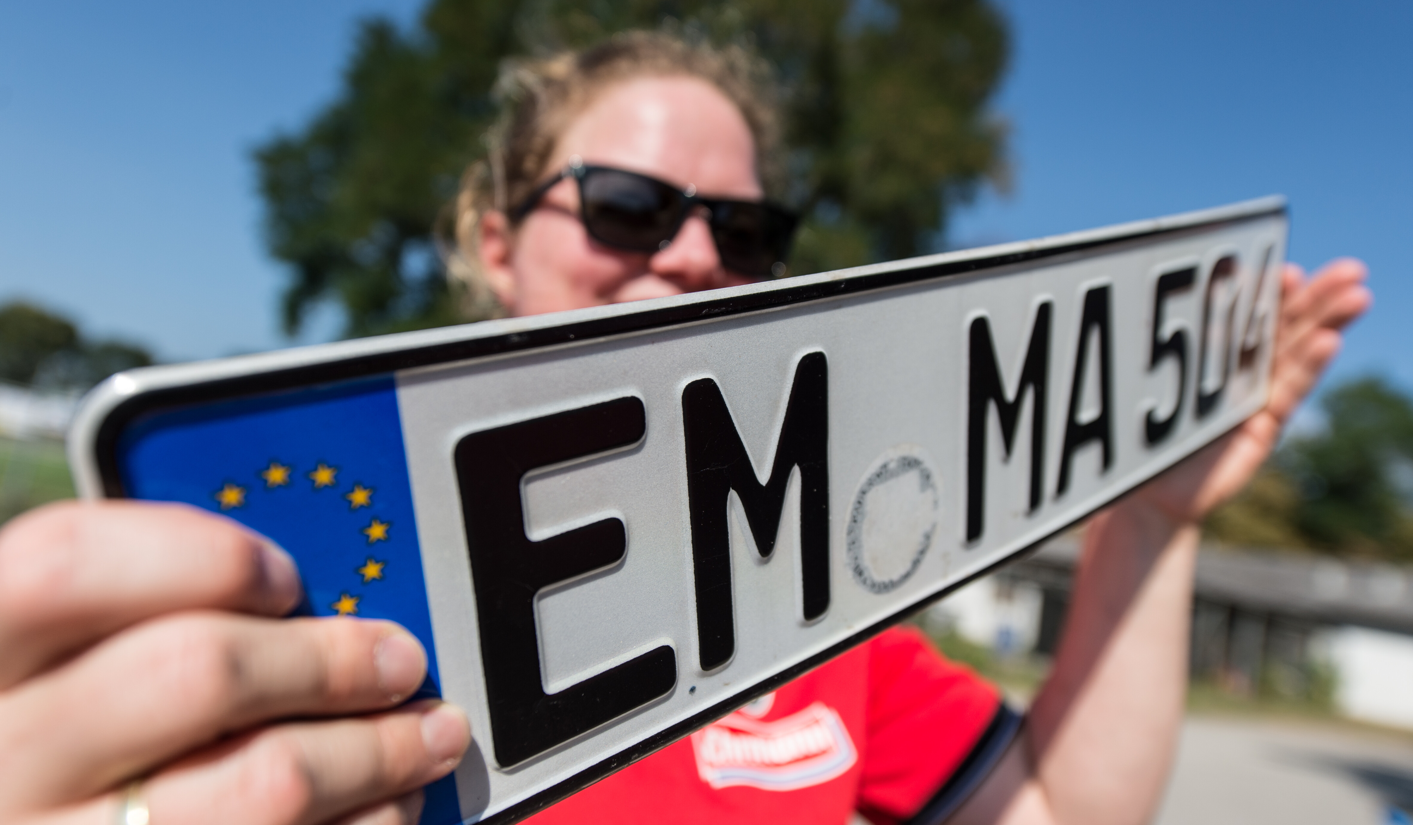 Eine Frau hält ein Wunschkennzeichen mit der Aufschrift "EM-MA 504" hoch.
