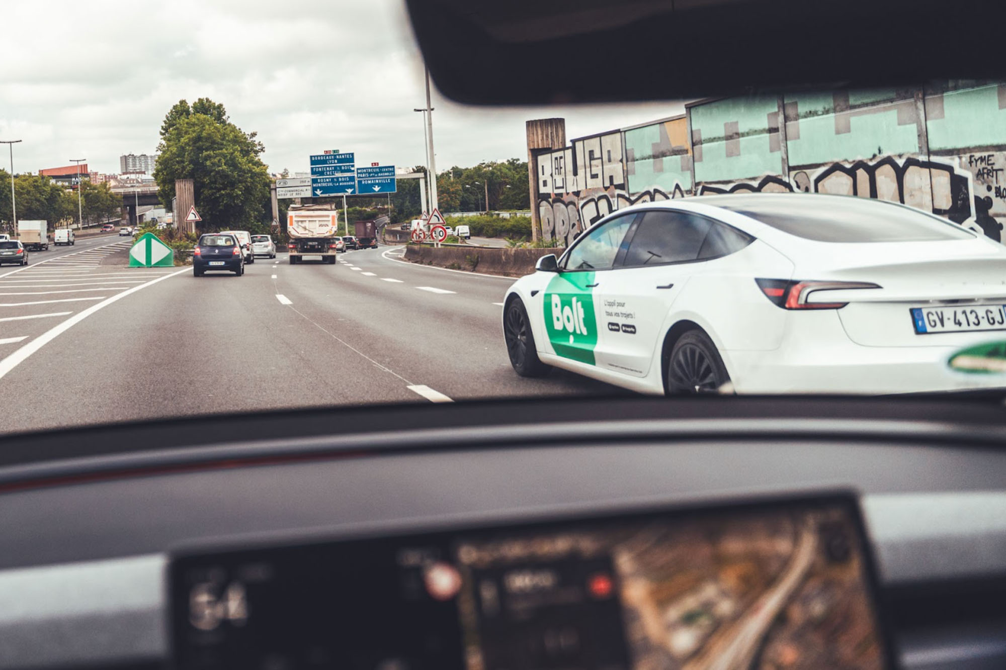 Ein weißes Tesla Model Y fährt auf einer Großstadtautobahn 