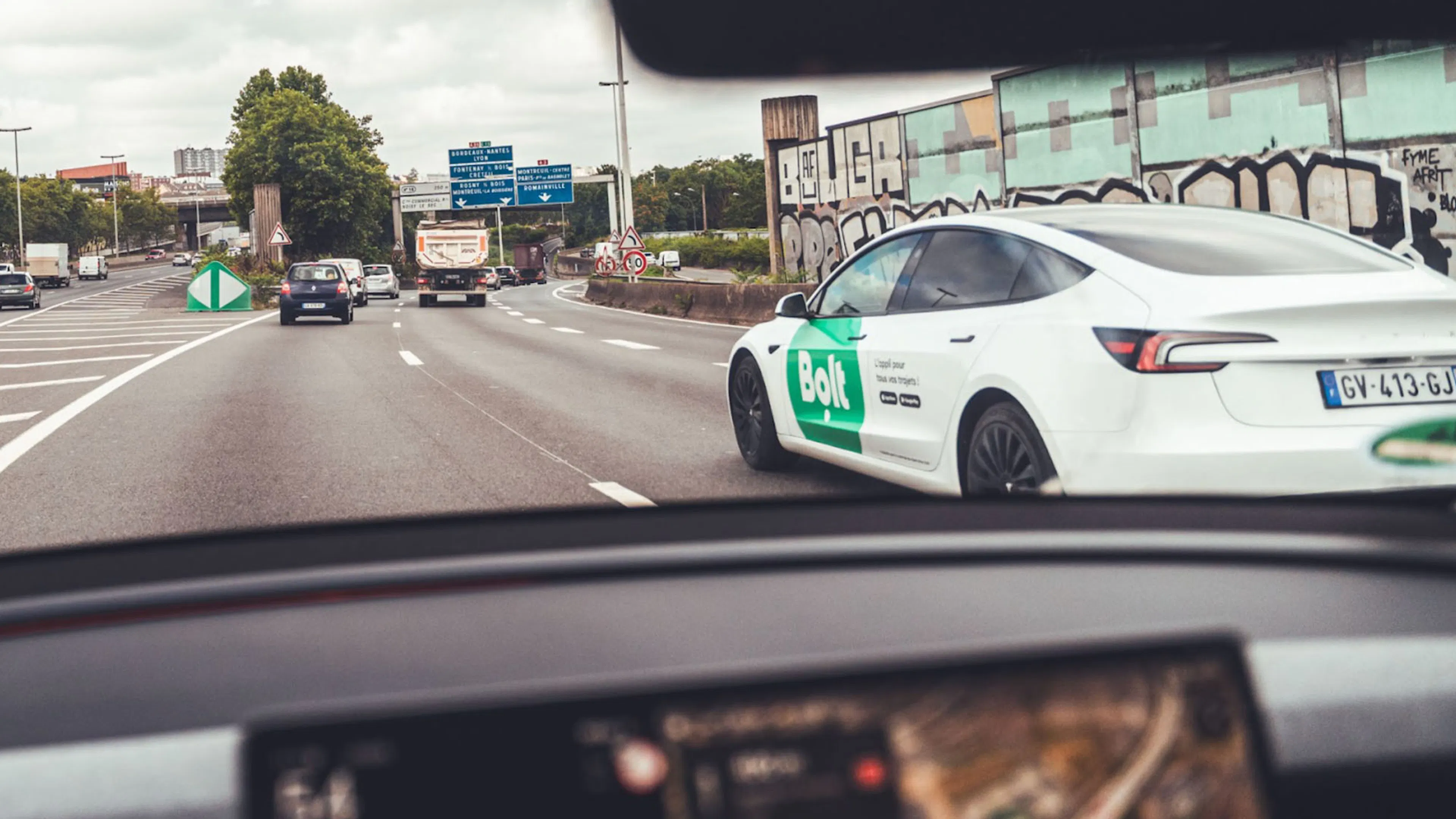 Ein weißes Tesla Model Y fährt auf einer Großstadtautobahn