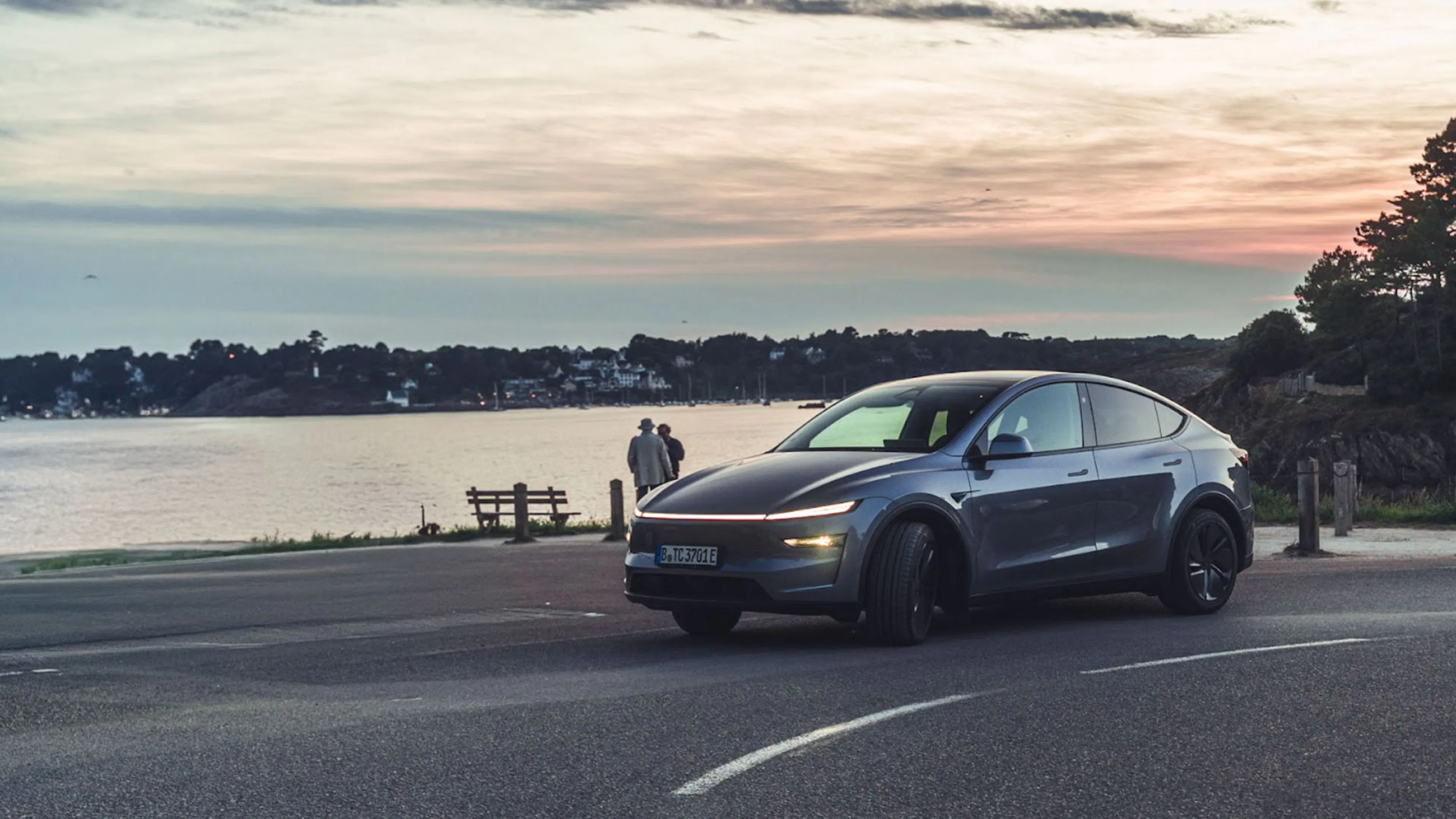 Ein dunkelgraues Tesla Model Y parkt vor malerischer Kulisse am Meer
