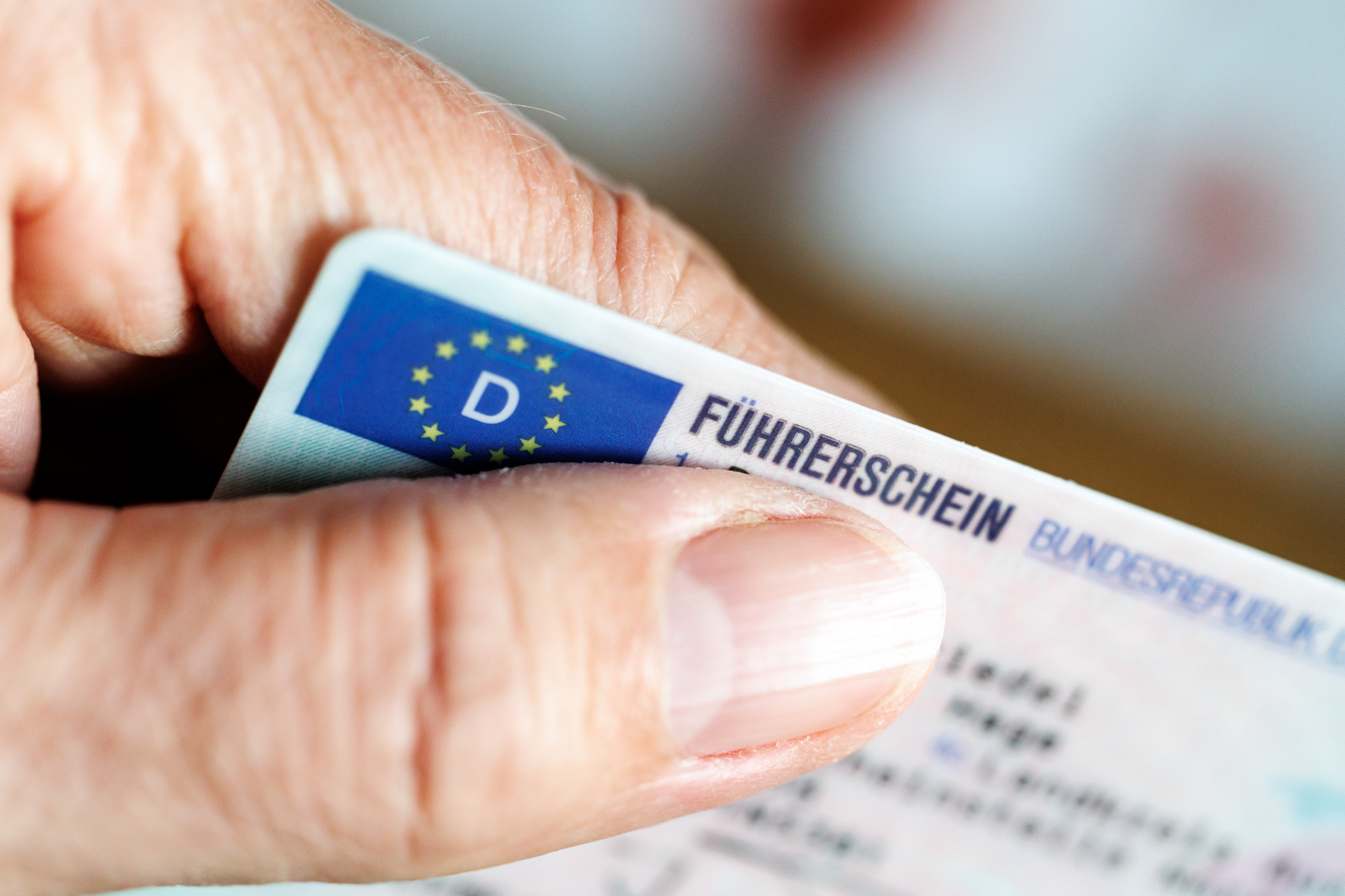 Eine Hand hält einen deutschen Führerschein im Scheckkartenformat.
