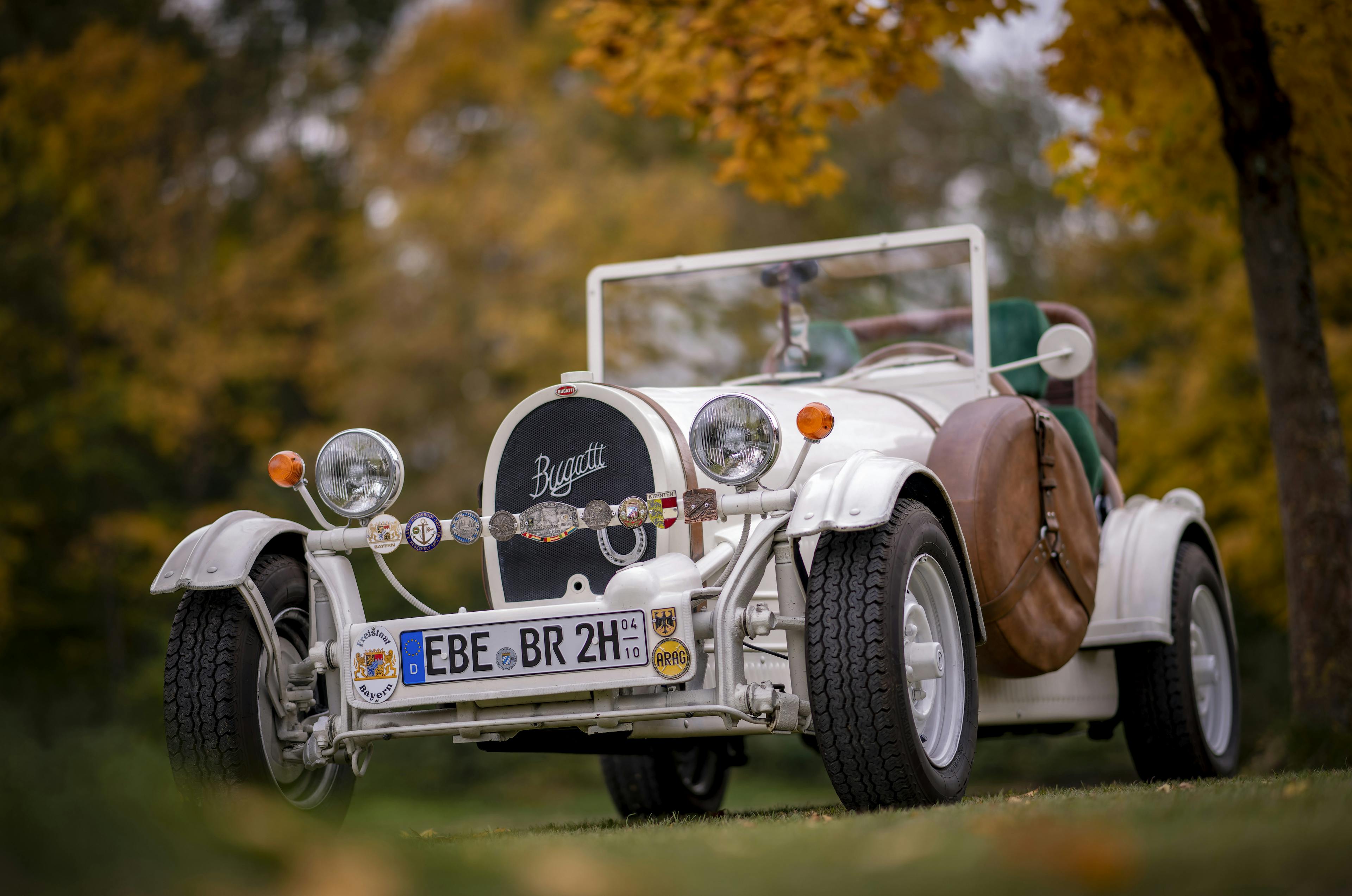 Nachbau eines 1923er Bugatti 35 B steht auf einer Wiese vor Bäumen mit Herbstlaub.