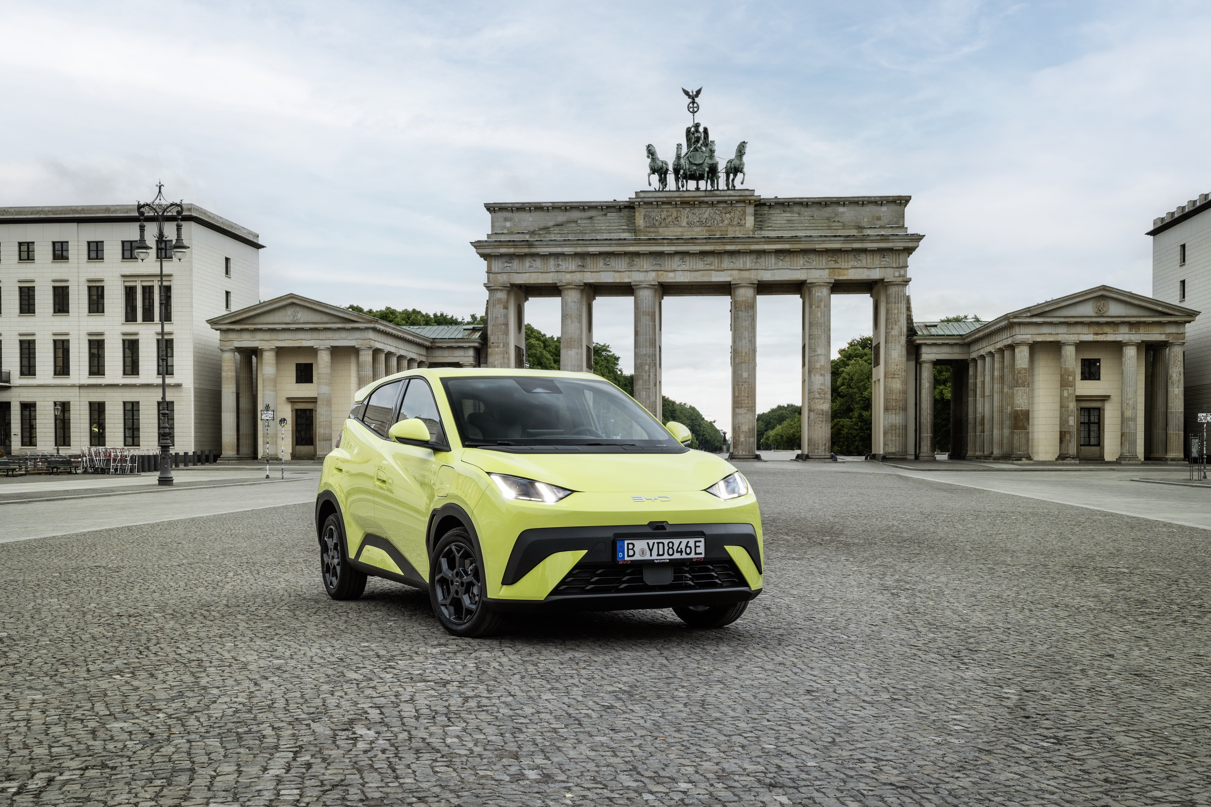 Ein grell grüner BYD Dolphin Surf steht vor dem Brandenburger Tor in Berlin