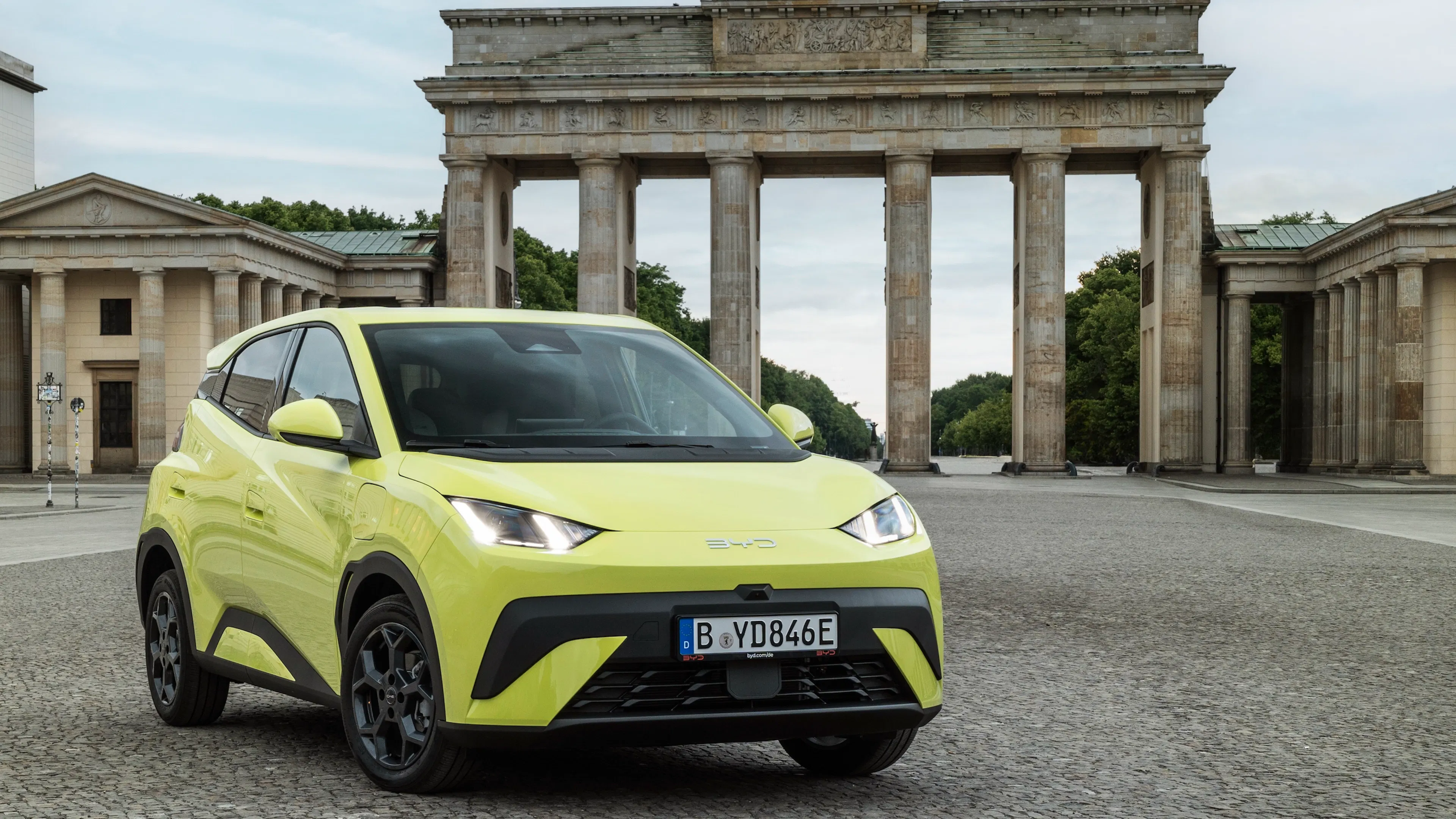 Ein grell grüner BYD Dolphin Surf steht vor dem Brandenburger Tor in Berlin