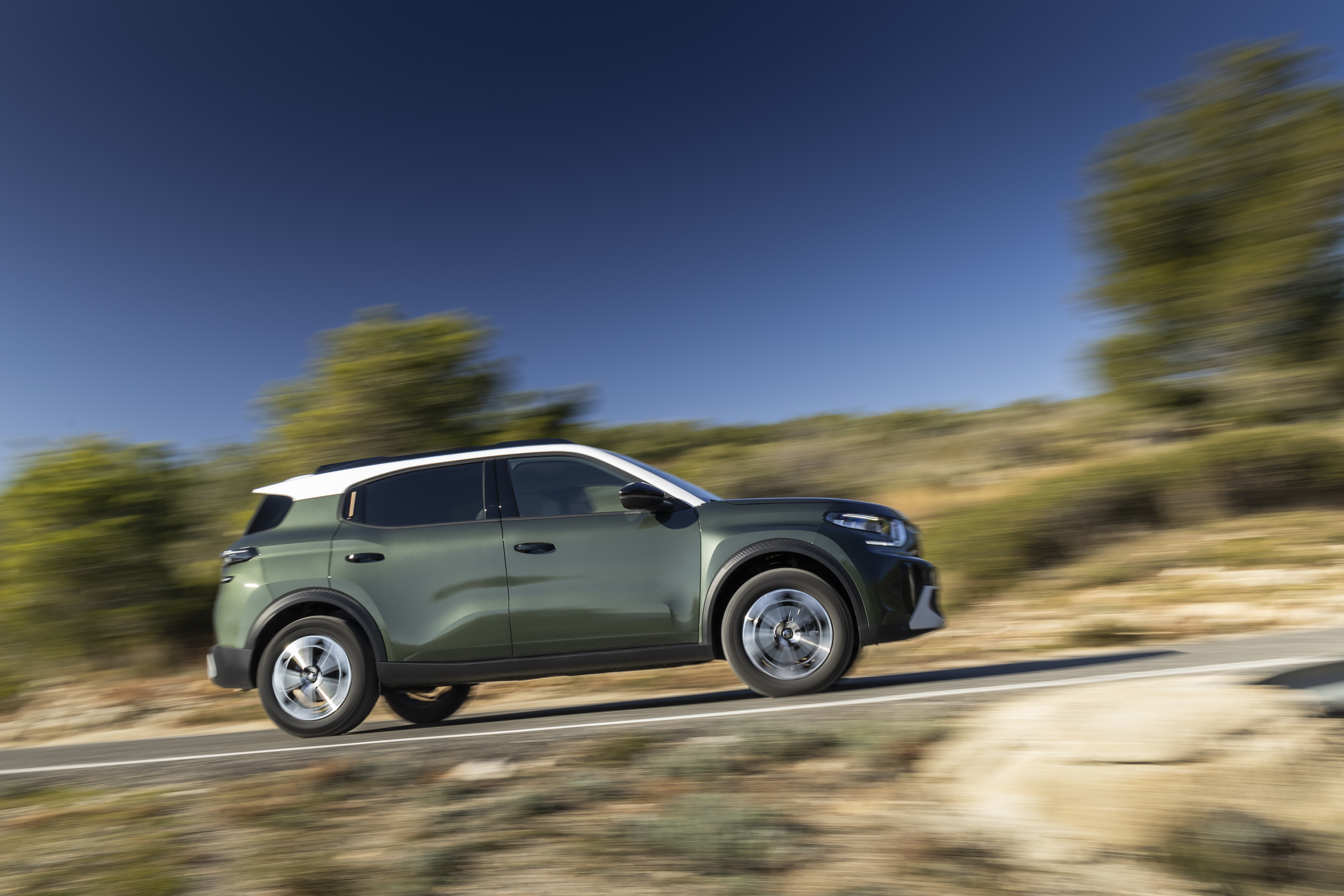 Ein grüner Citroën ë-C3 Aircross fährt auf einer Landstraße.