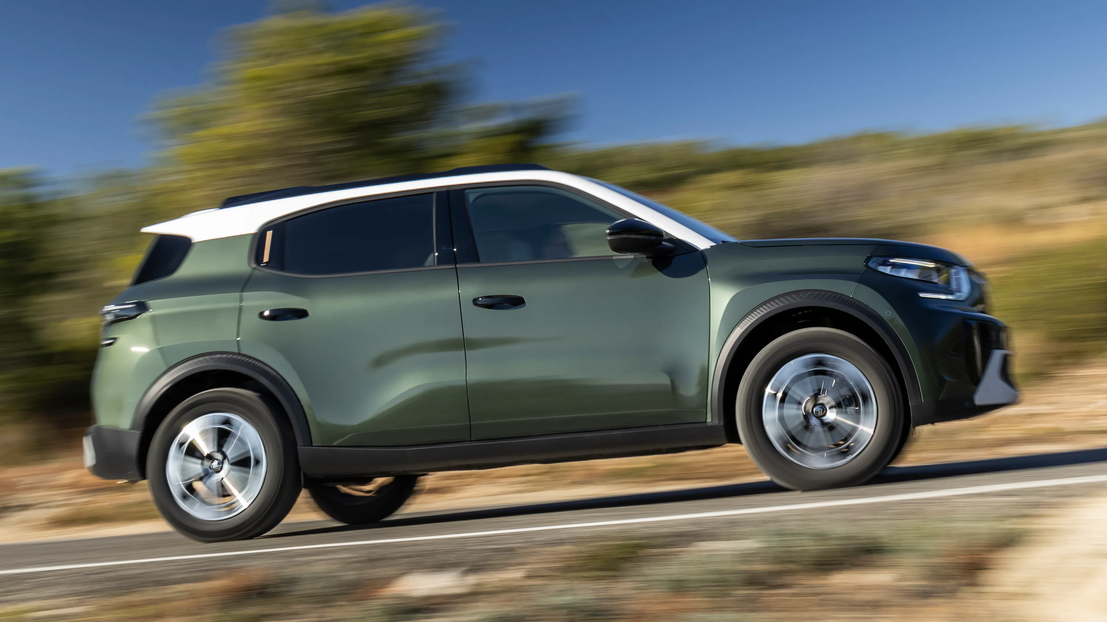 Ein grüner Citroën ë-C3 Aircross fährt auf einer Landstraße.