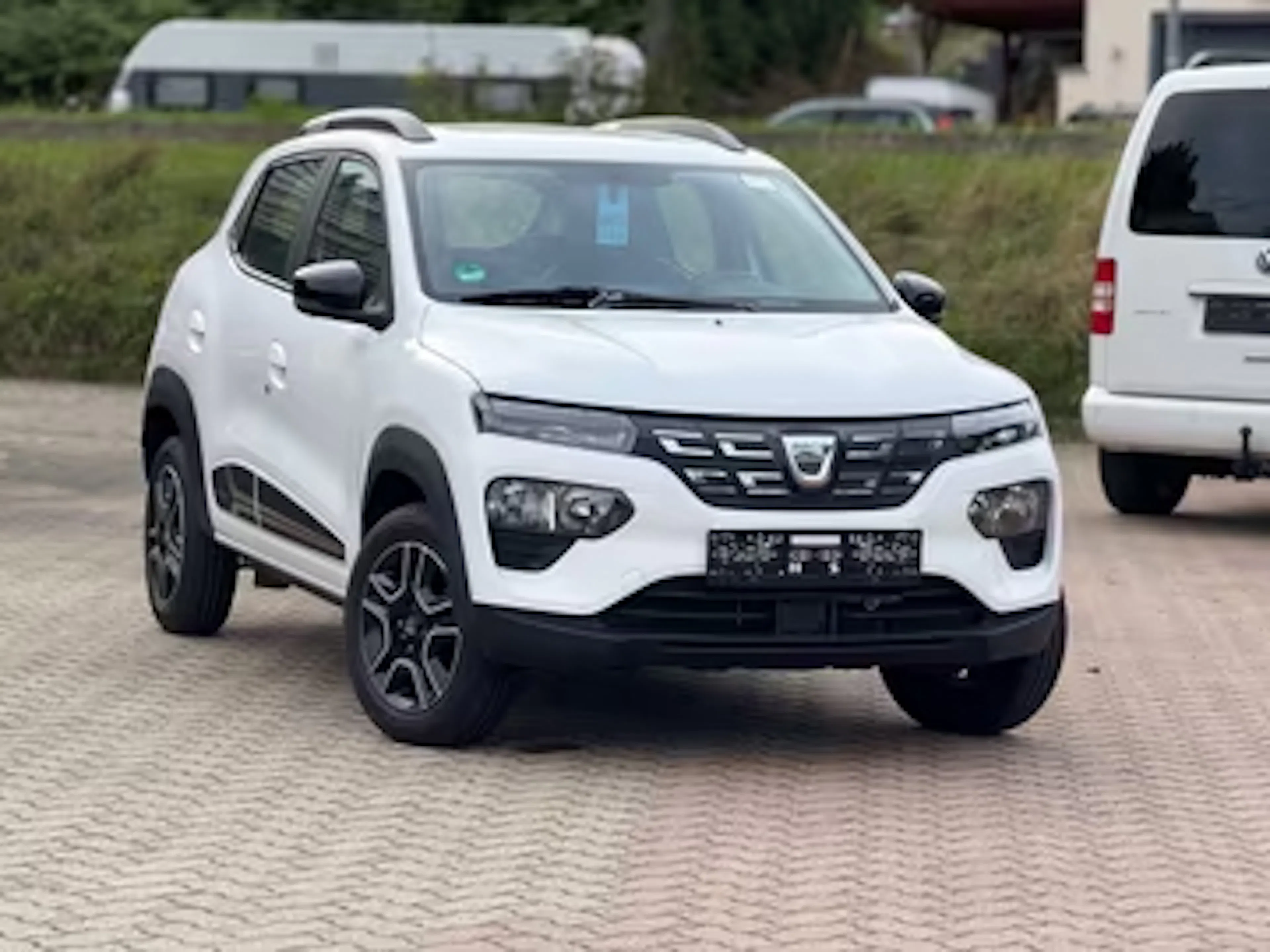Weißer Dacia Spring auf einem Parkplatz