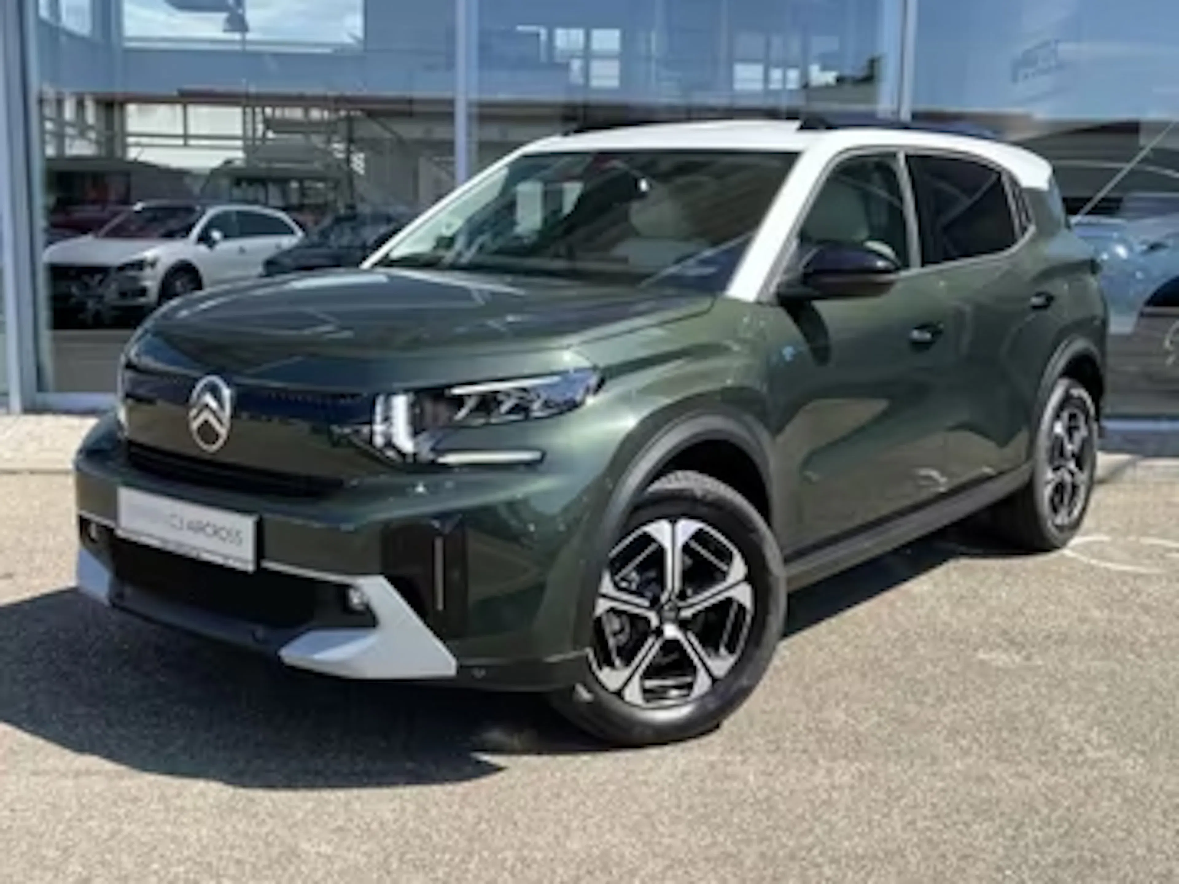 Ein dunkelgrüner Citroën ë-C3 Aircross steht vor einem Autohaus.