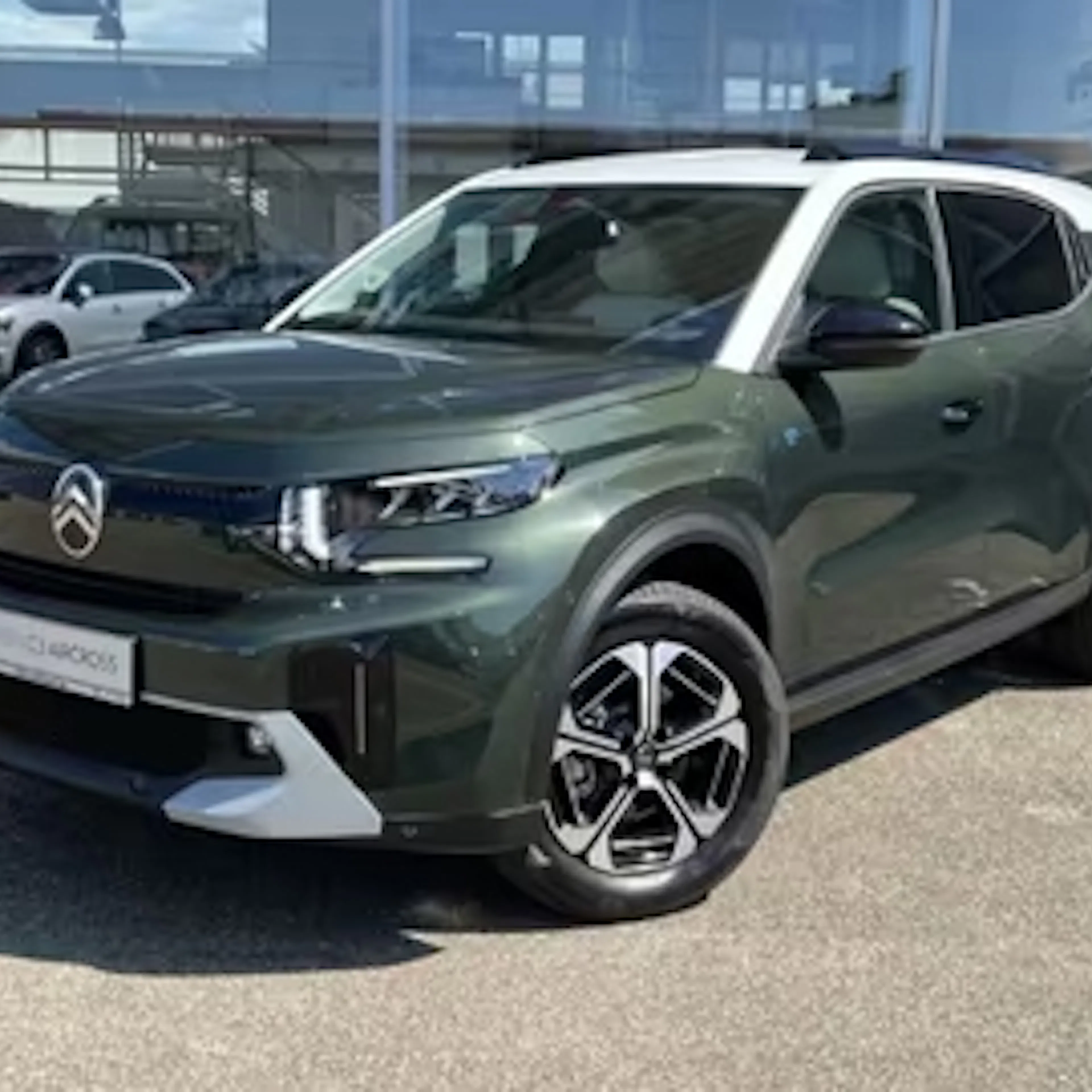 Ein dunkelgrüner Citroën ë-C3 Aircross steht vor einem Autohaus.