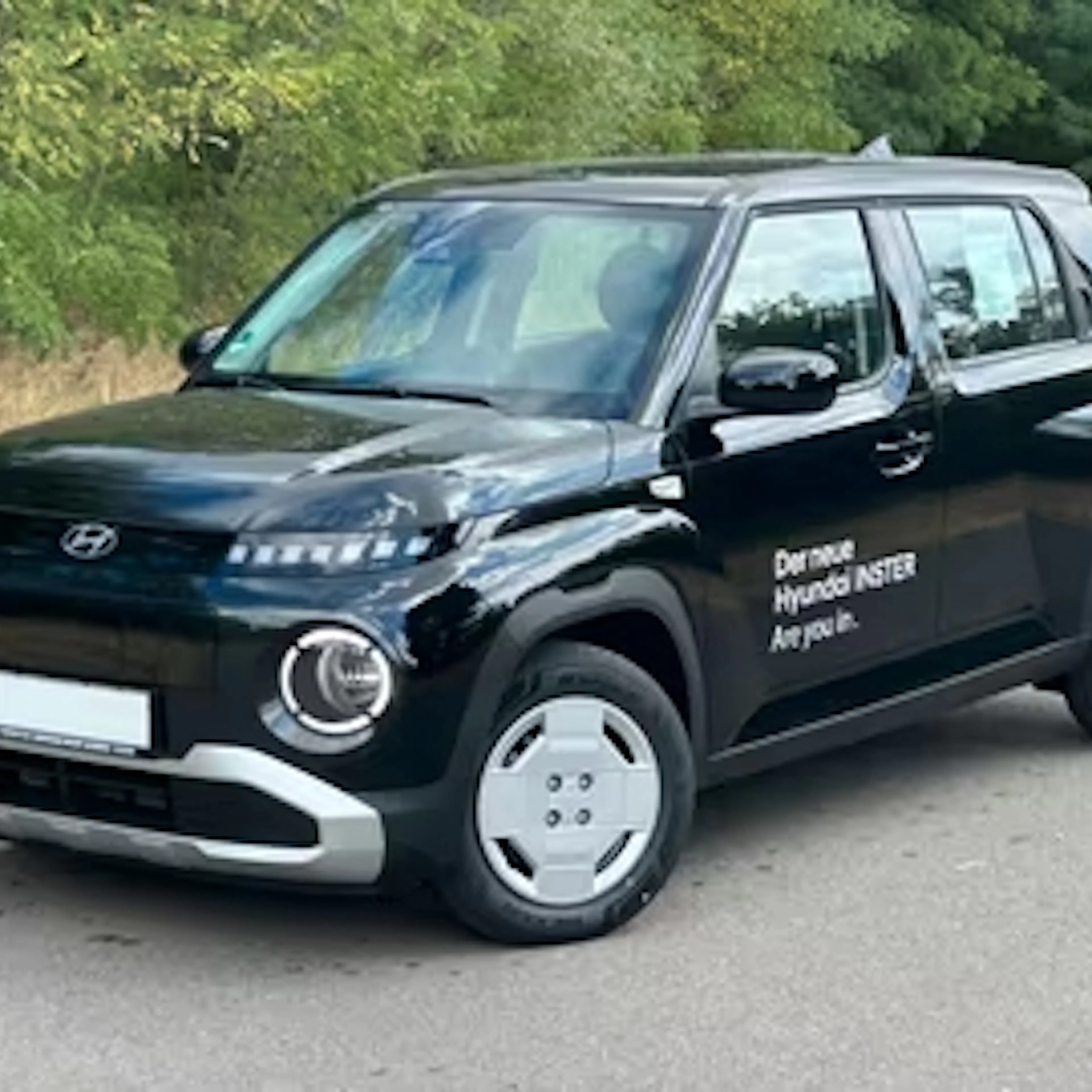 Ein schwarzer Hyundai Inster steht auf einer Straße.