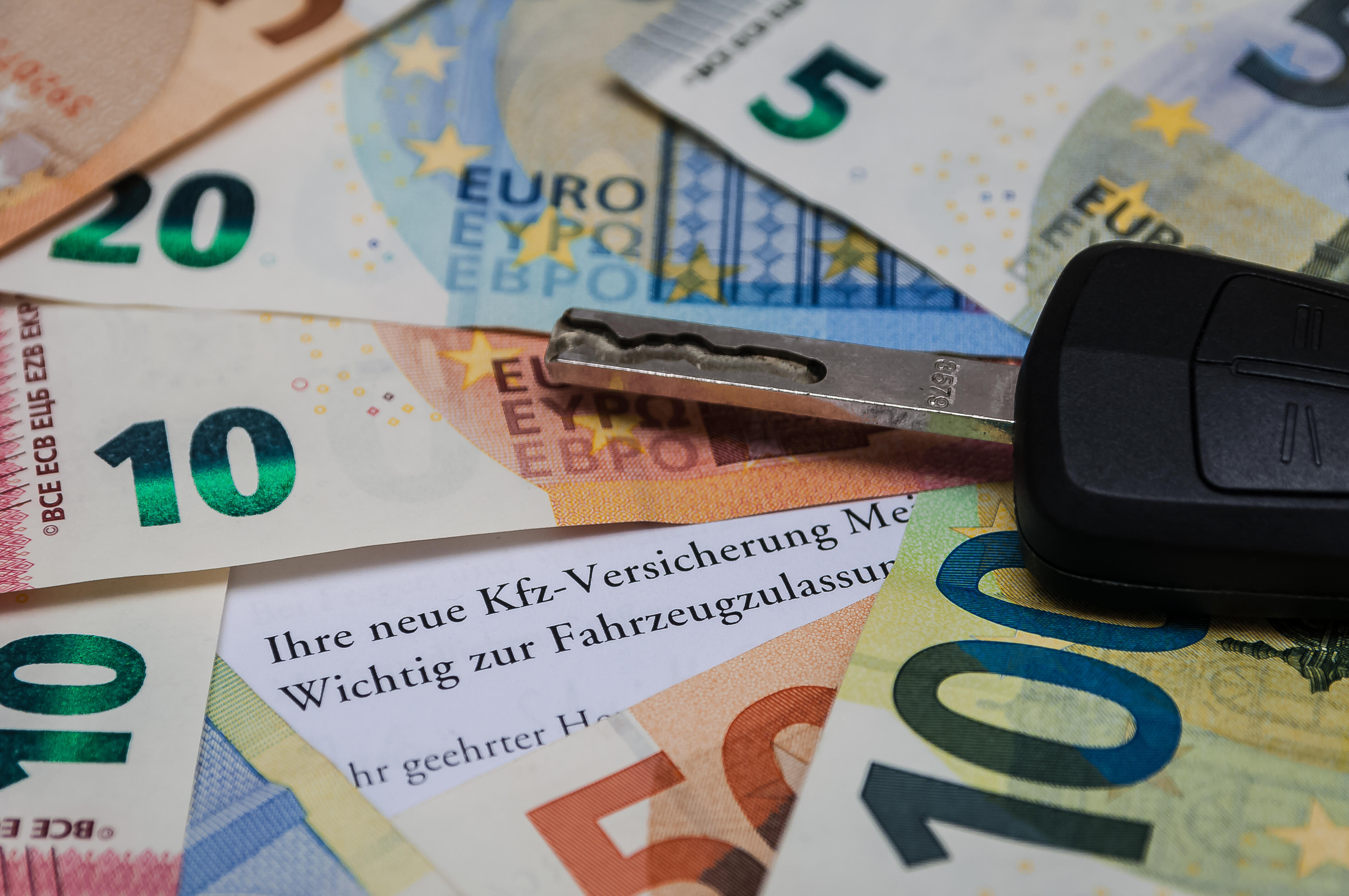 Ein Autoschlüssel liegt zwischen Geldscheinen