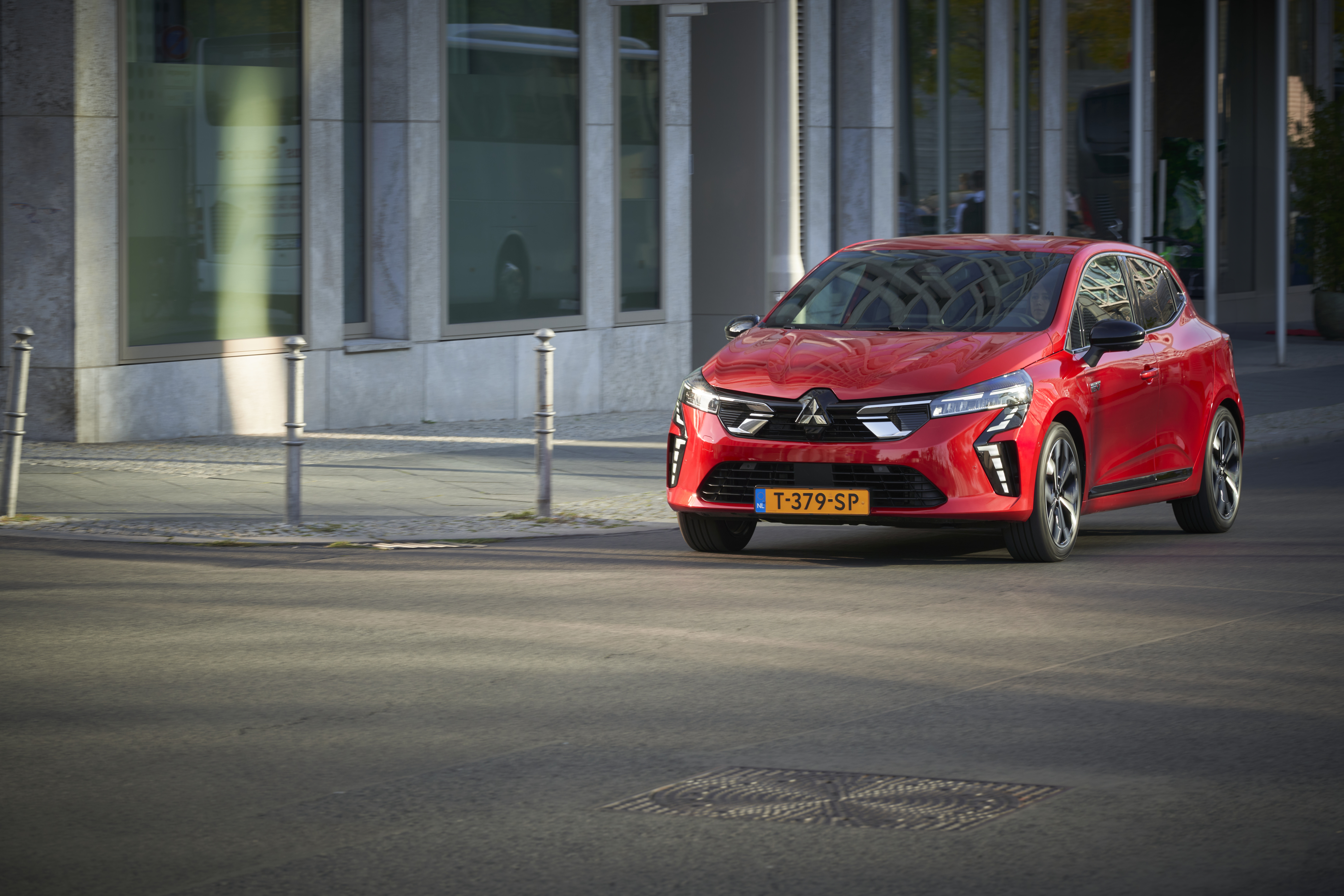 Ein roter Mitsubishi Colt fährt auf einer asphaltierten Straße