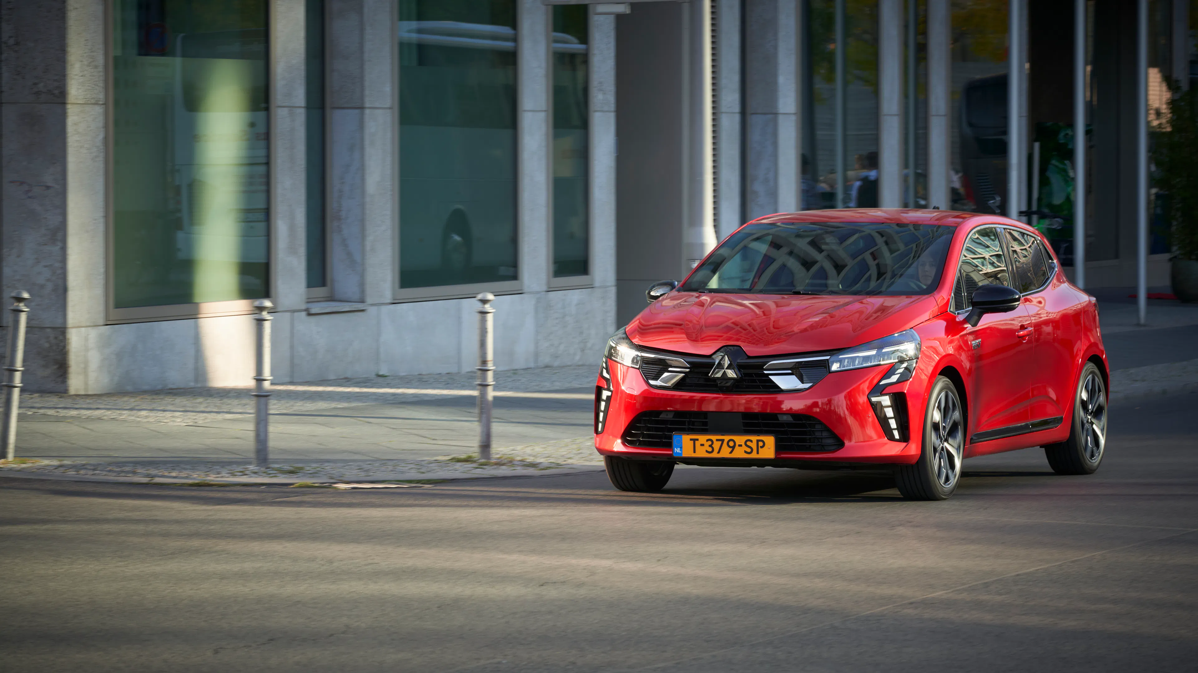 Ein roter Mitsubishi Colt fährt auf einer asphaltierten Straße