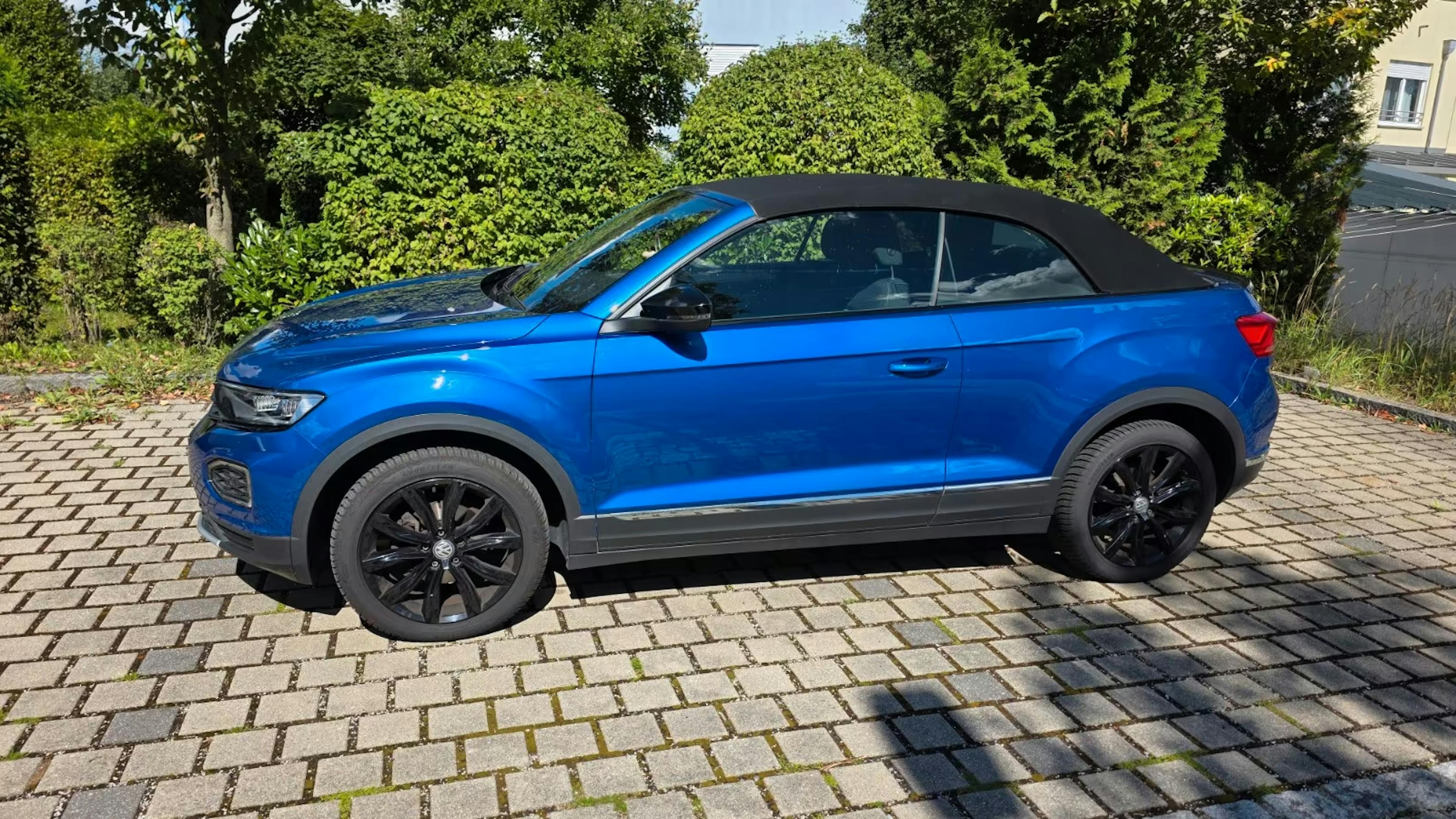 Ein blauer VW T-Roc-Cabrio steht auf einem gepflasterten Platz.