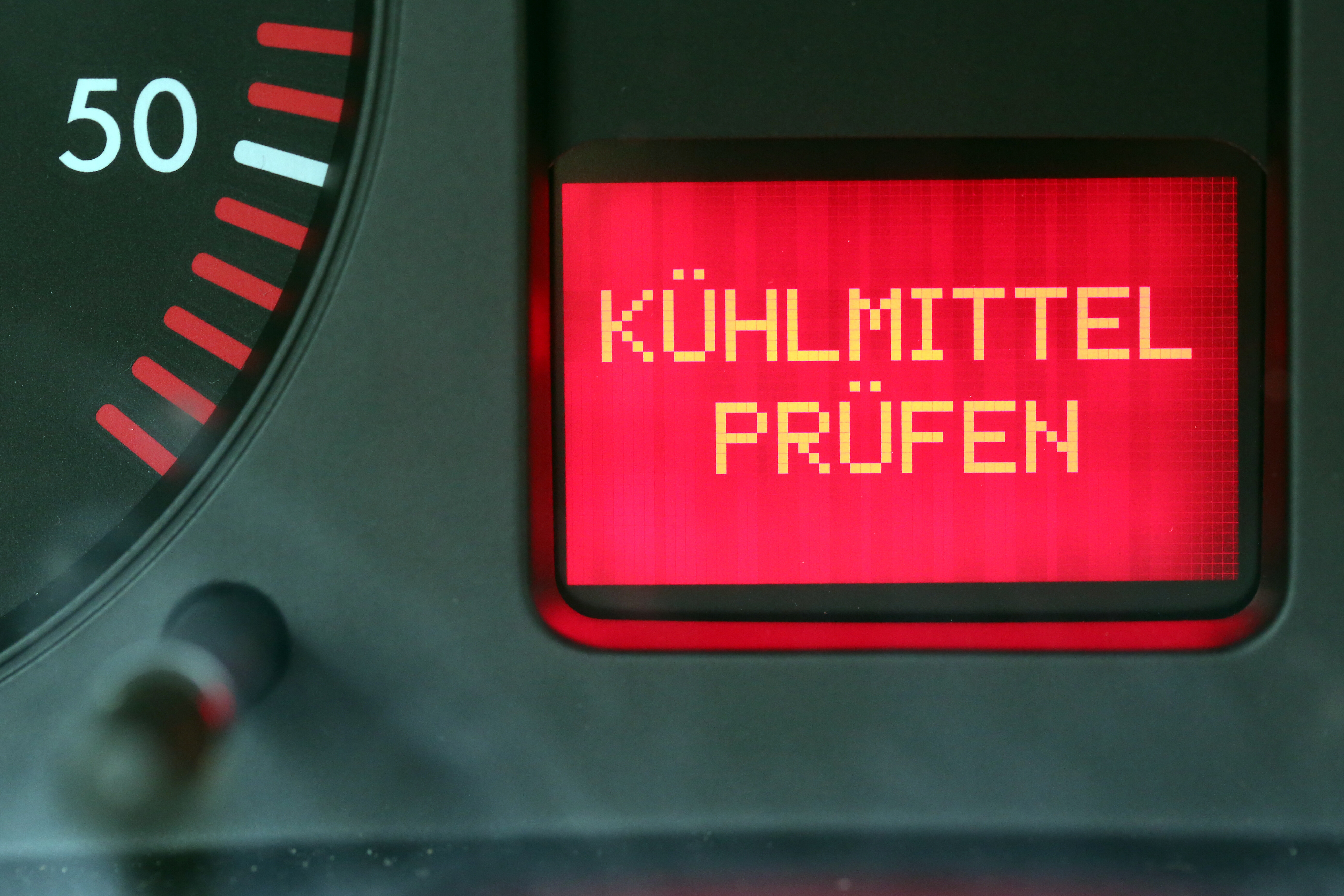 Im Cockpit eines Autos leuchtet die Warnleuchte "Kühlmittel prüfen" auf.