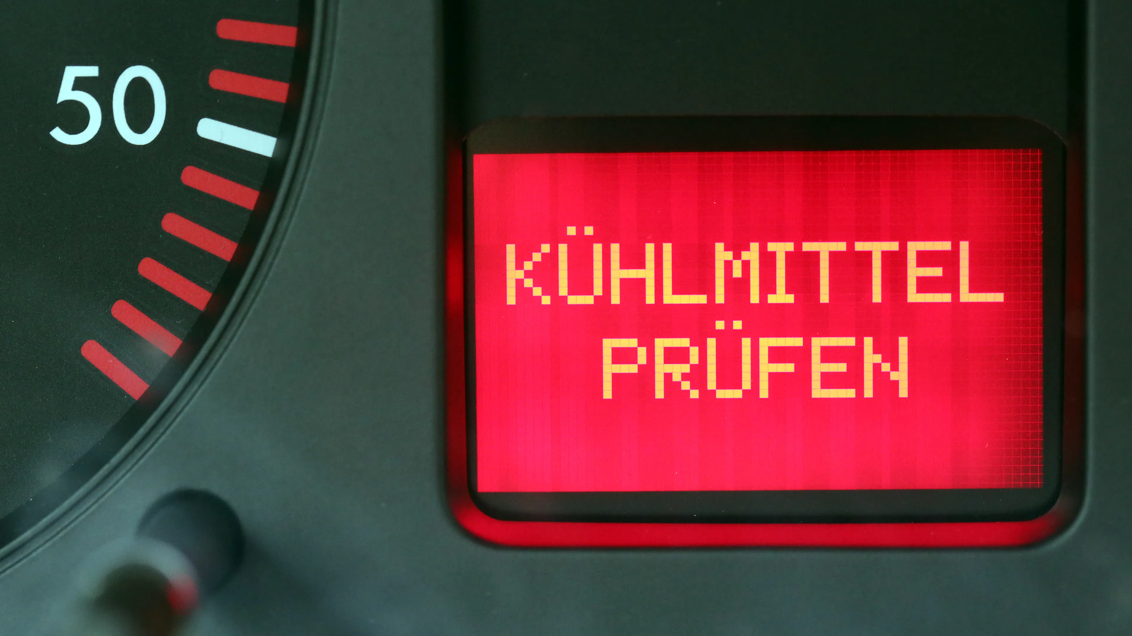 Im Cockpit eines Autos leuchtet die Warnleuchte "Kühlmittel prüfen" auf.