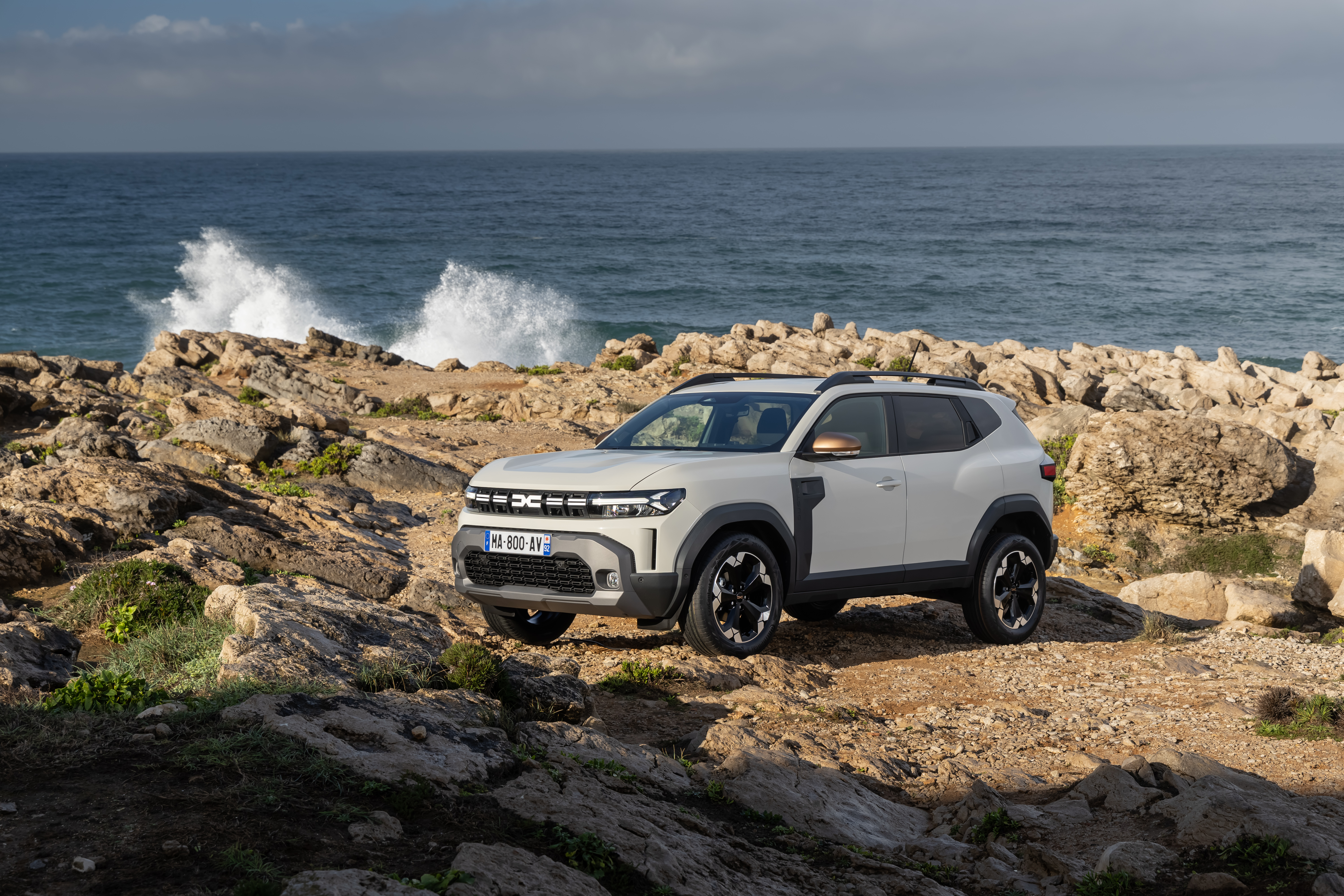 Ein hell lackierter Dacia Duster steht an der Küste