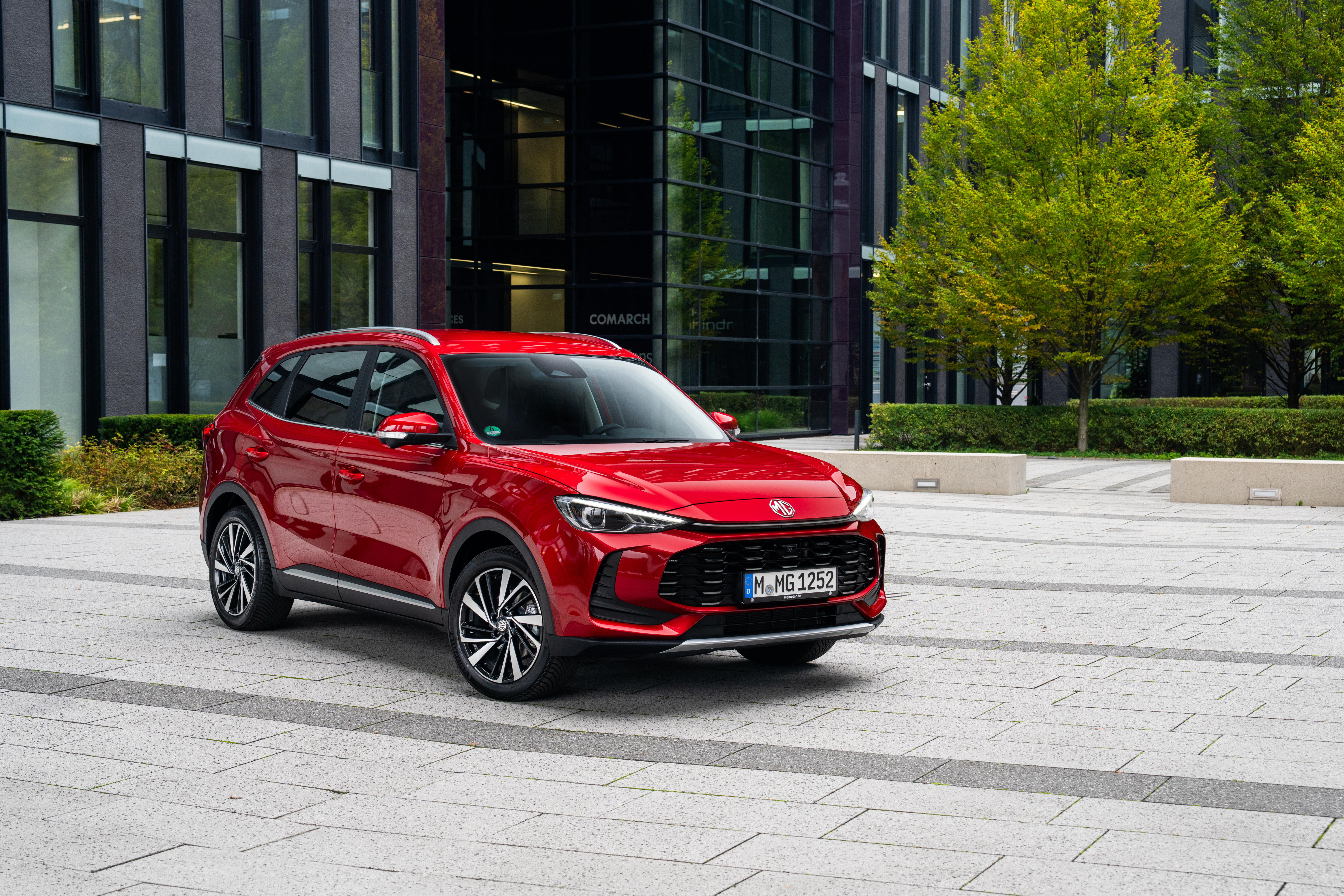 Ein roter MG ZS steht auf einer Parkfläche vor einem modernen Haus