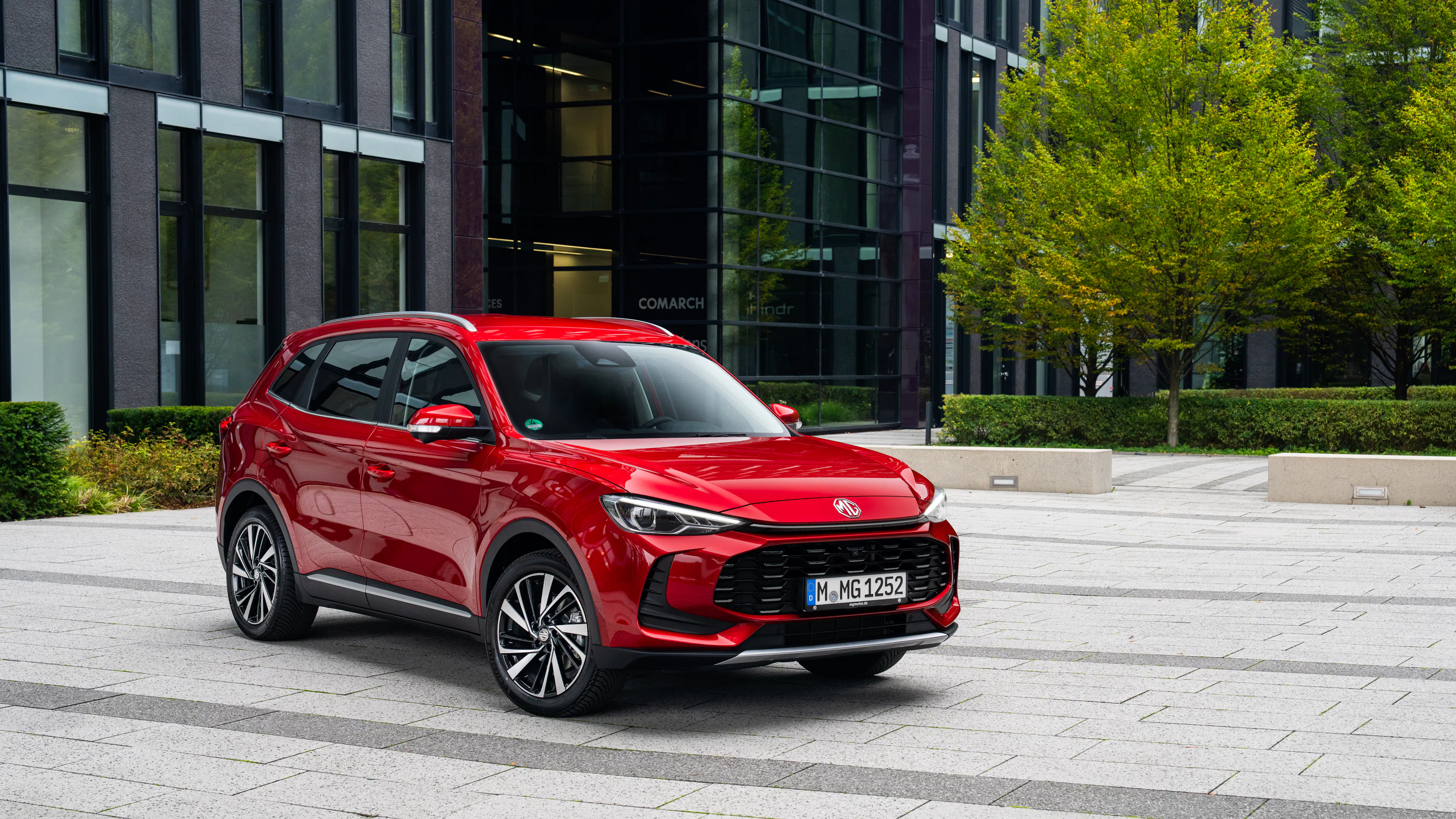 Ein roter MG ZS steht auf einer Parkfläche vor einem modernen Haus