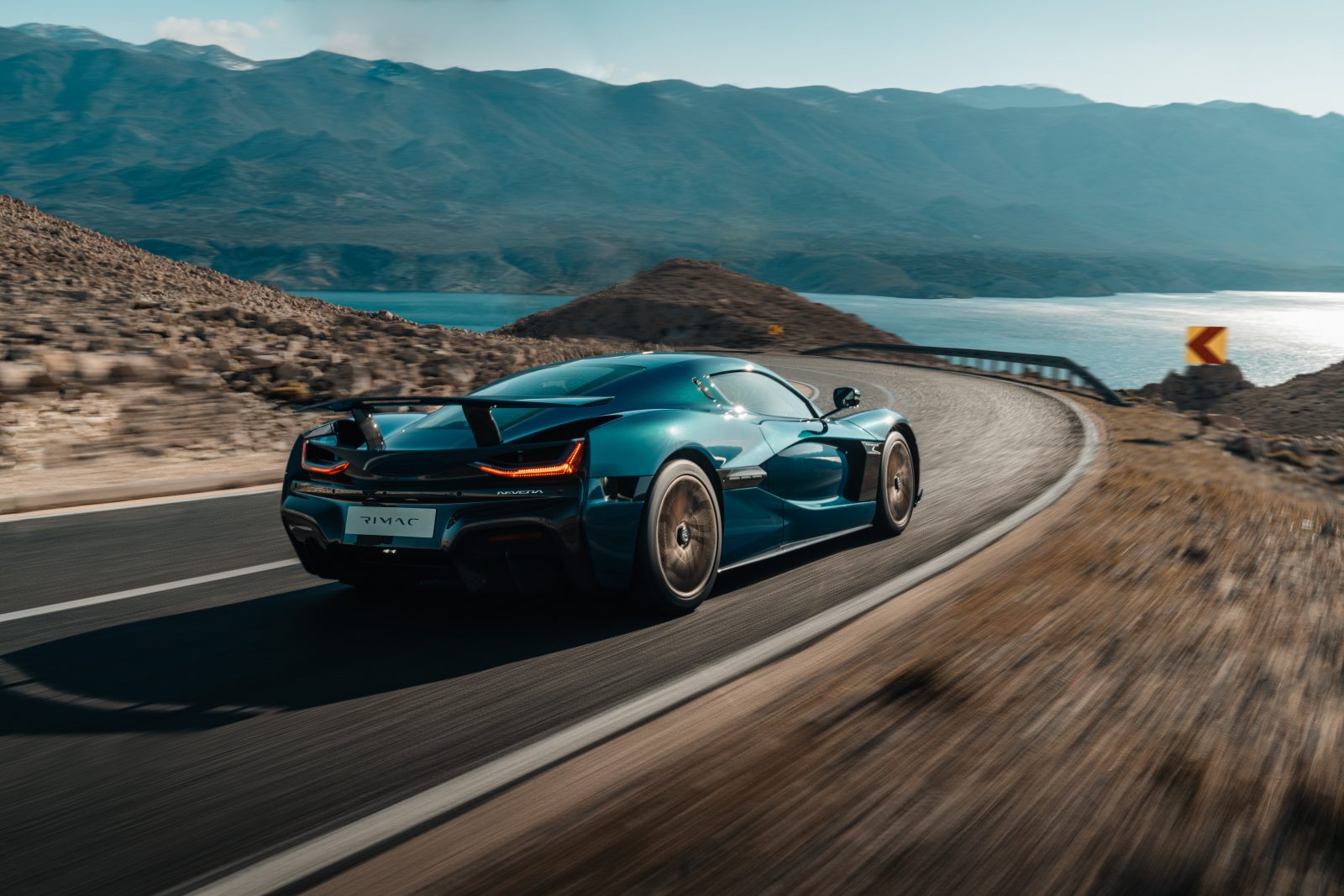 Ein petrolfarbener Rimac Nevera fährt eine Küstenstraße entlang
