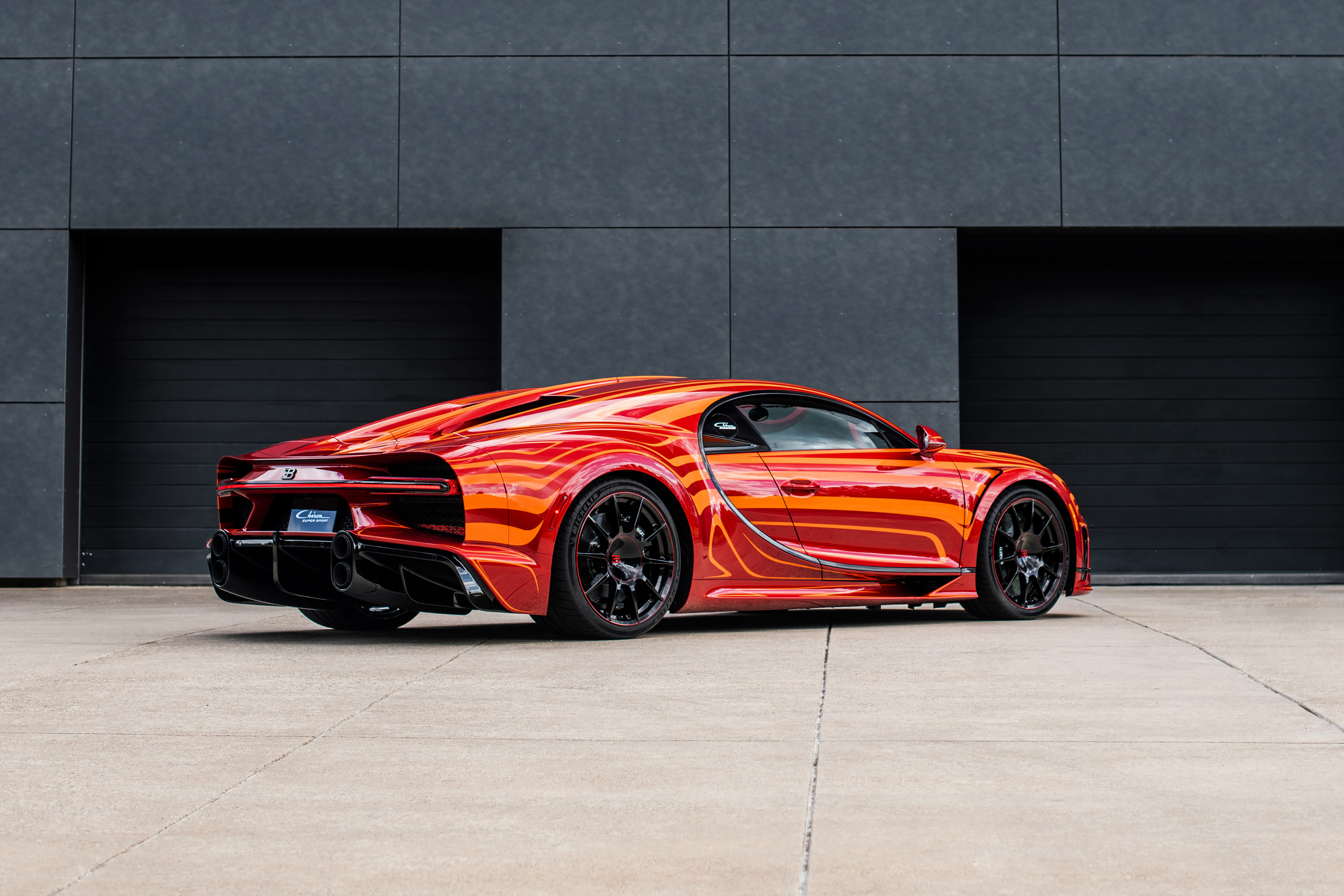 Ein roter Bugatti Chiron Super Sport steht vor einer Garageneinfahrt