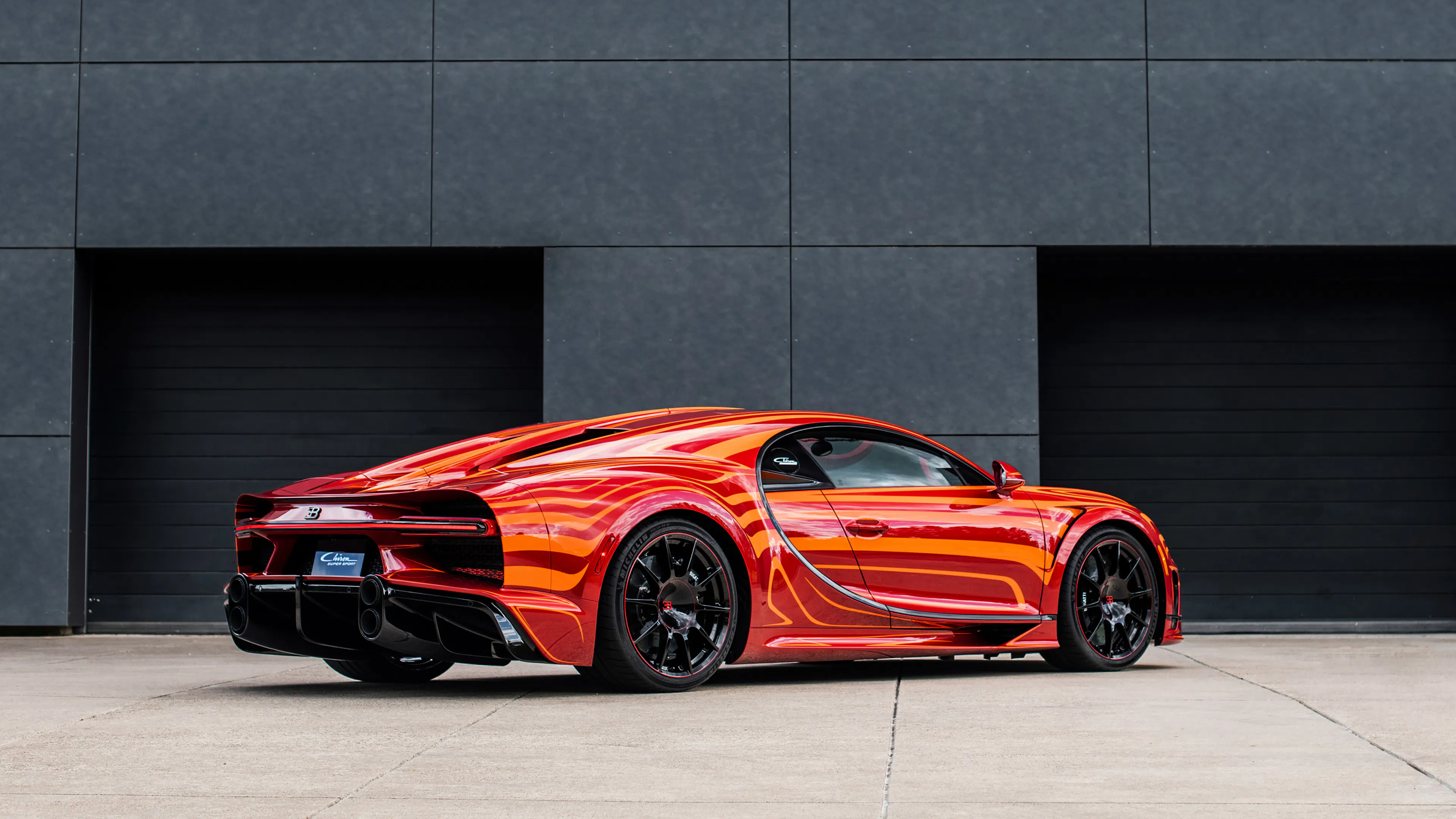 Ein roter Bugatti Chiron Super Sport steht vor einer Garageneinfahrt