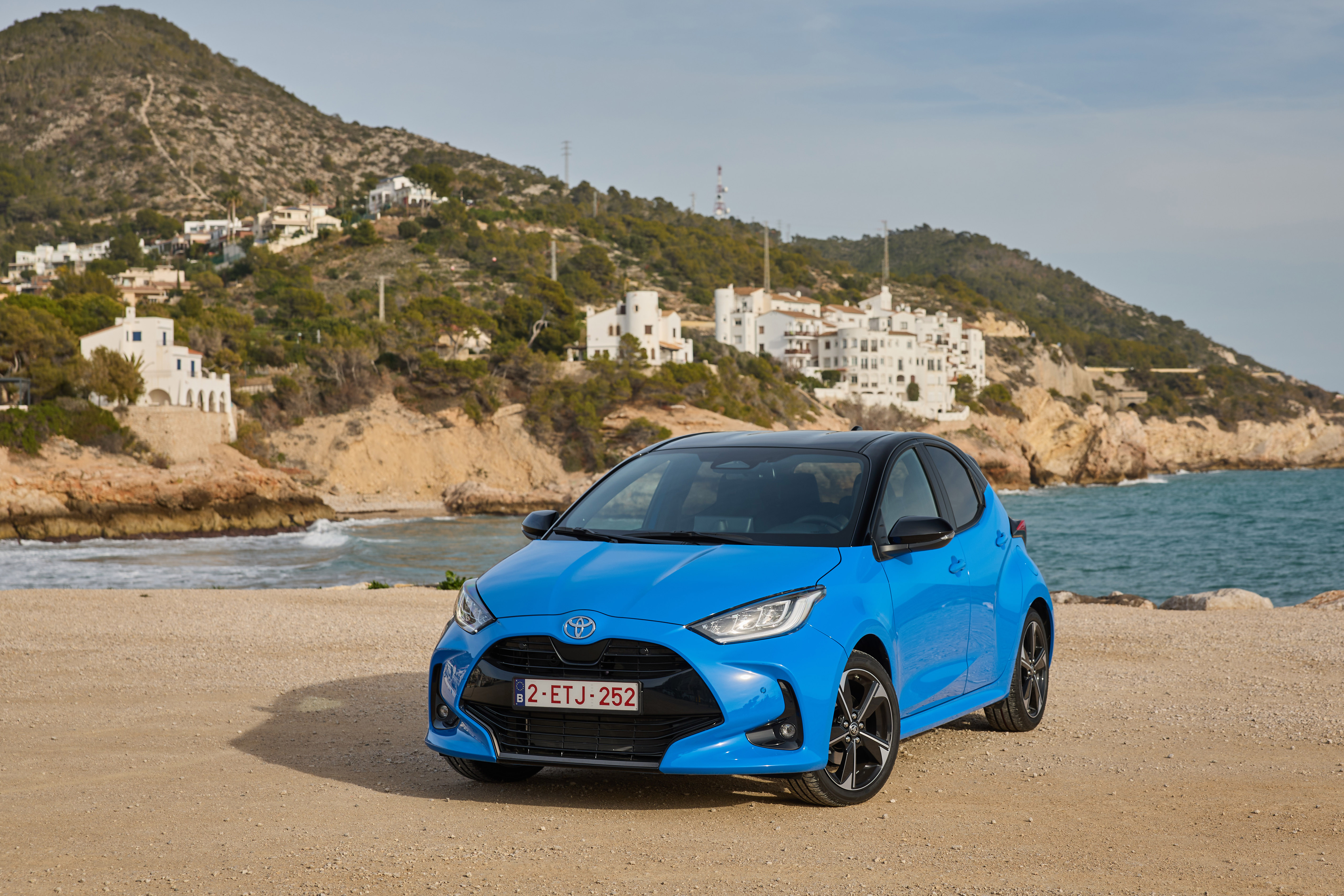 Ein blauer Toyota Yaris an einer bebauten Küste