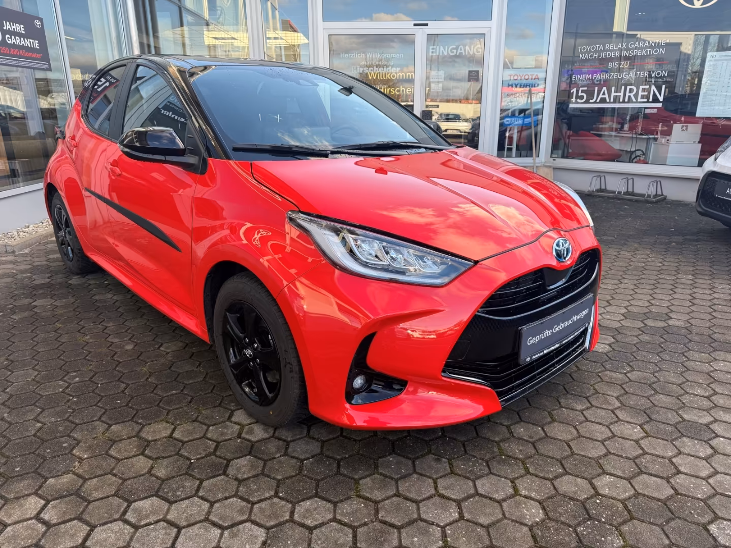Ein roter Toyota Yaris auf einer gepflasterten Fläche