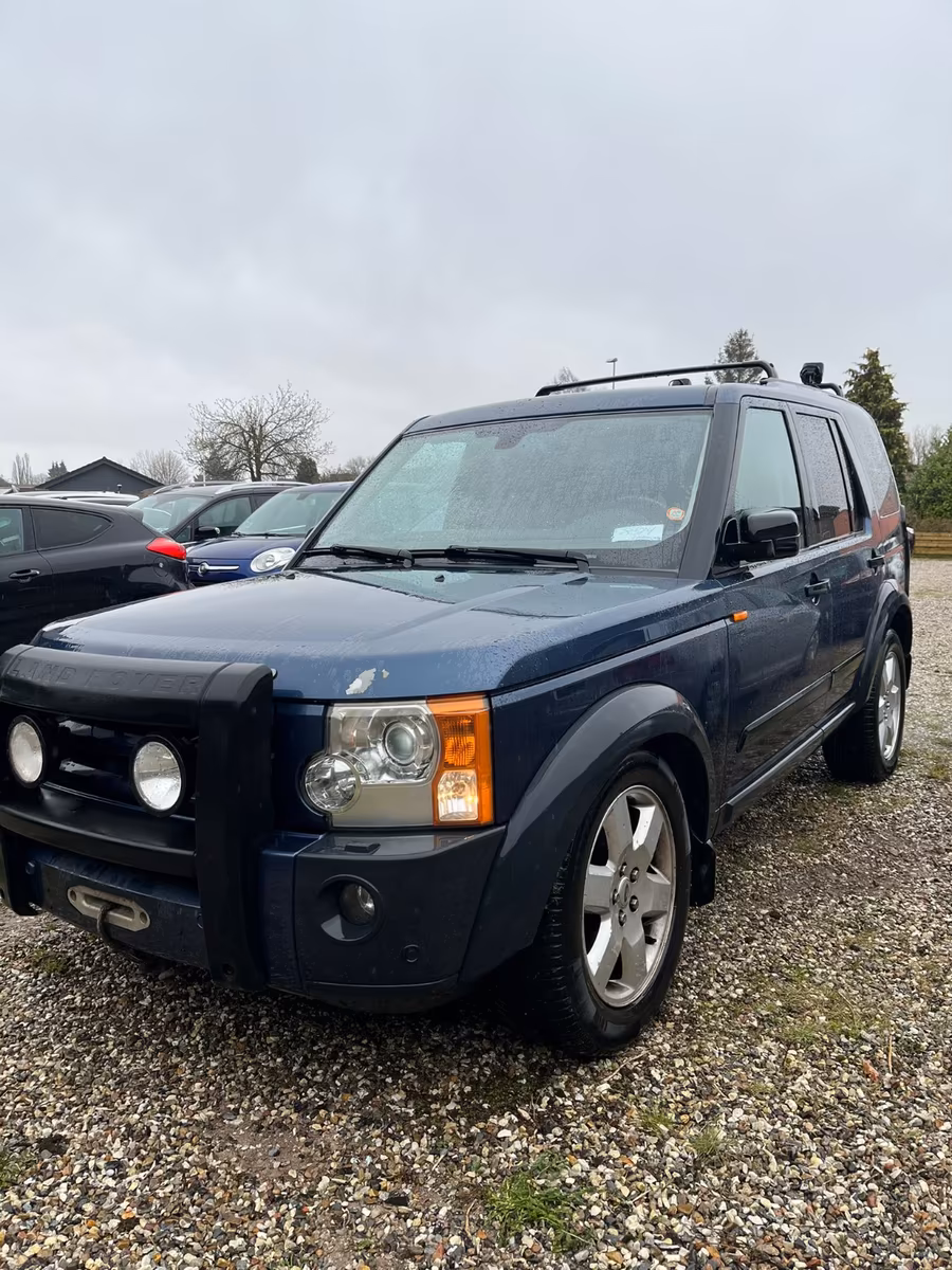 Blauer Land Rover Discovery auf Kiesplatz