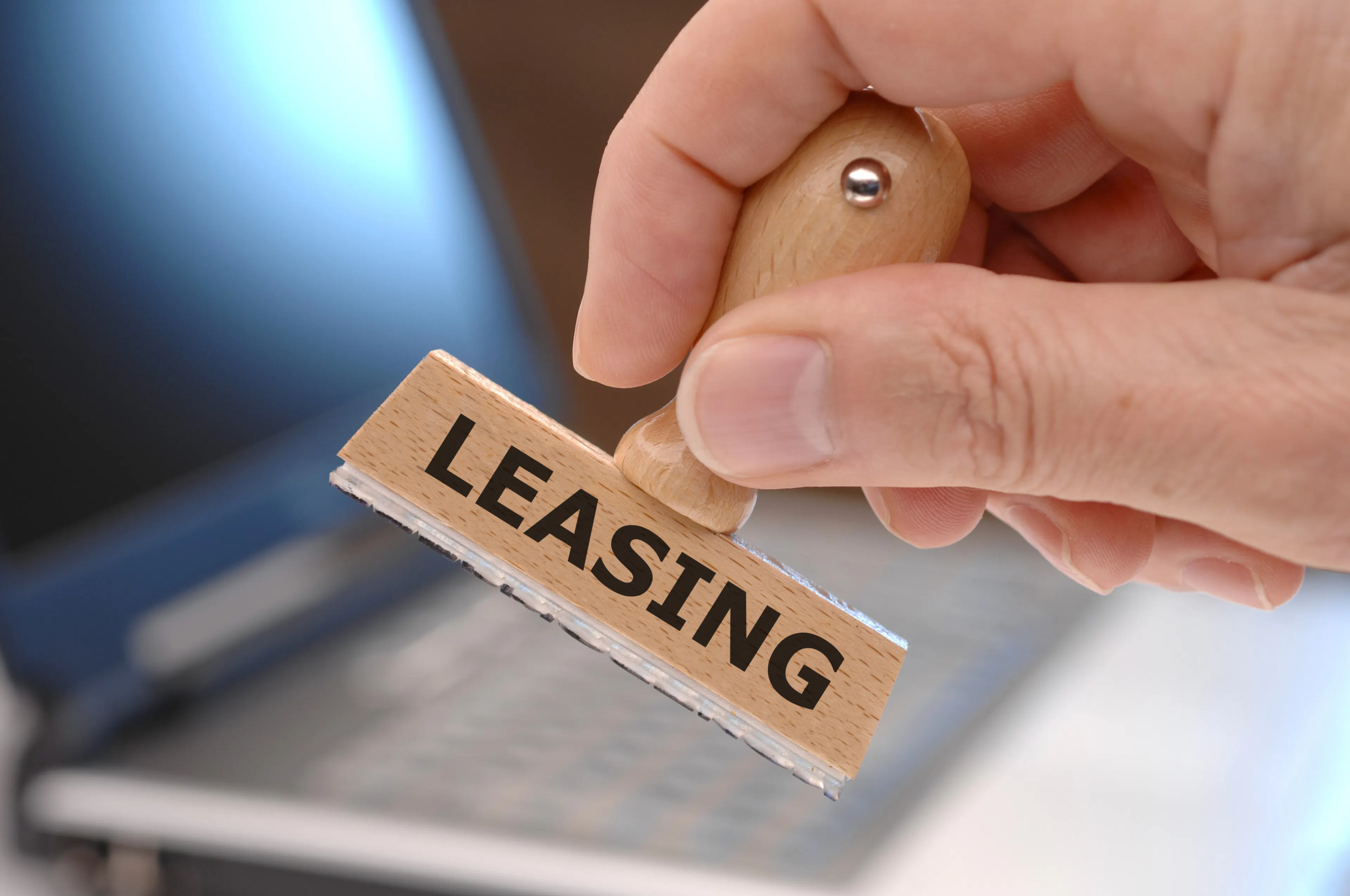 Eine Hand hält einen Stempel mit der Aufschrift "Leasing".