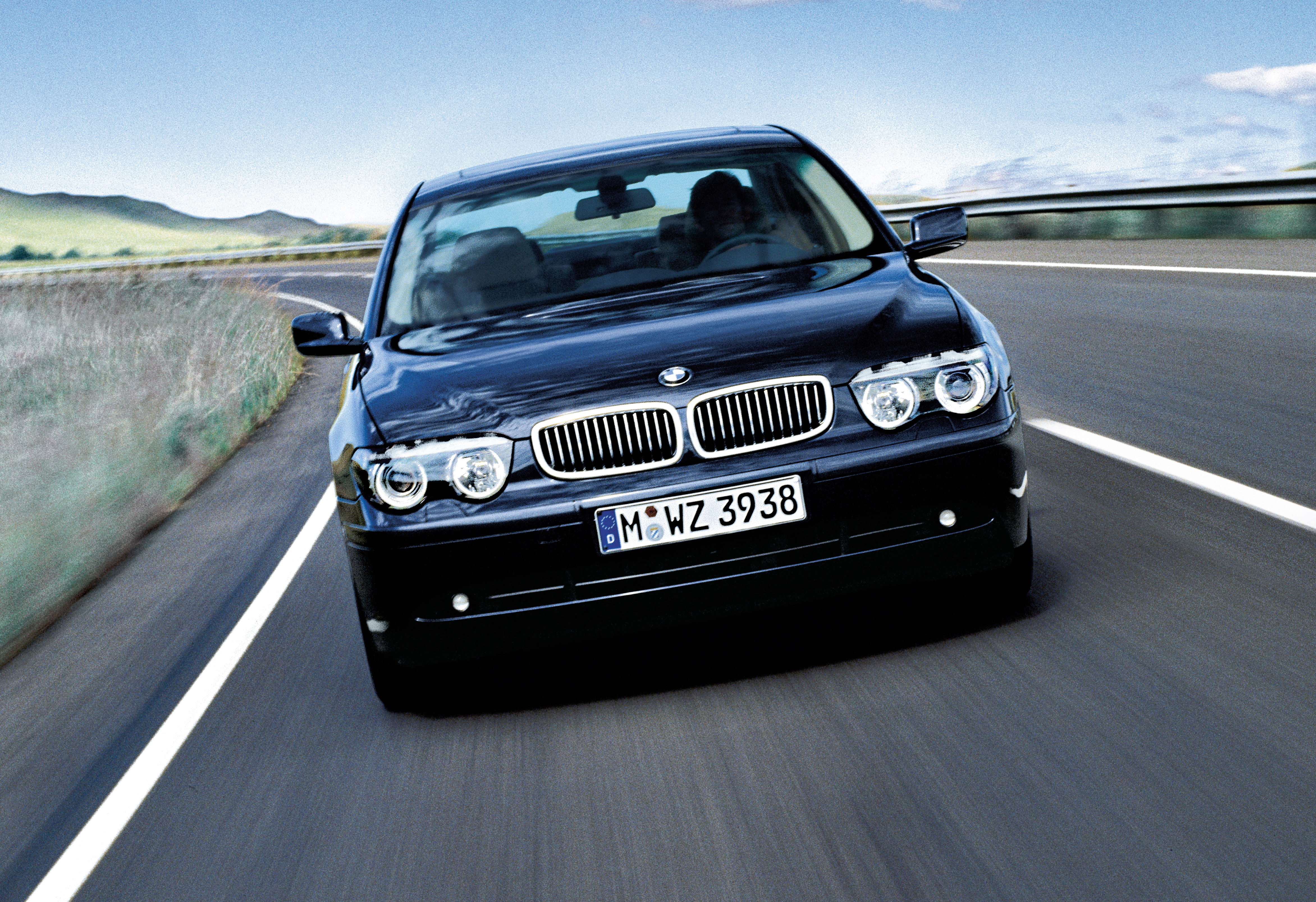 Ein schwarzer BMW 7er E65 fährt auf einer Landstraße.