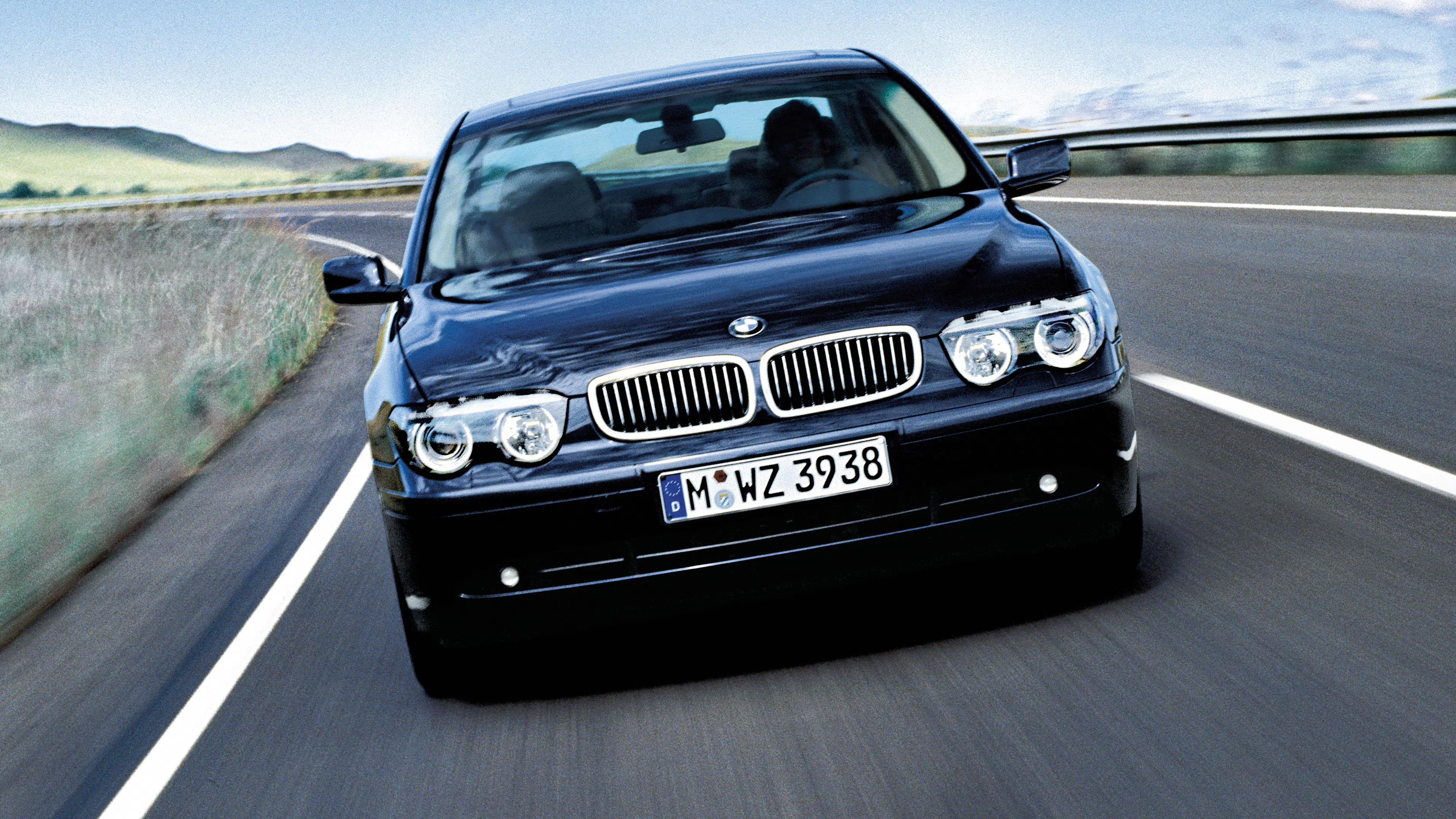 Ein schwarzer BMW 7er E65 fährt auf einer Landstraße.