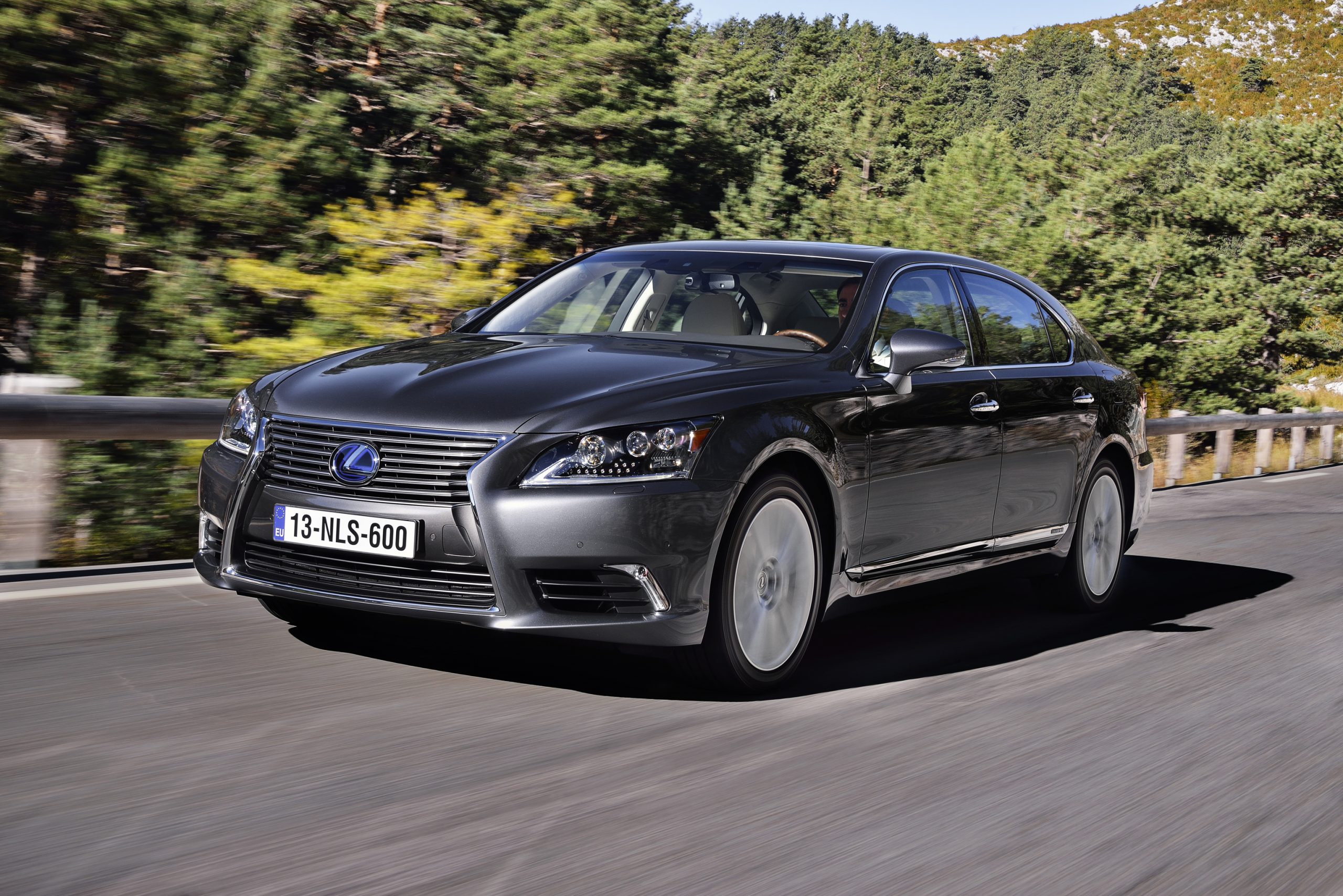 Ein schwarzer Lexus LS USF40 600H fährt auf einer Landstraße.