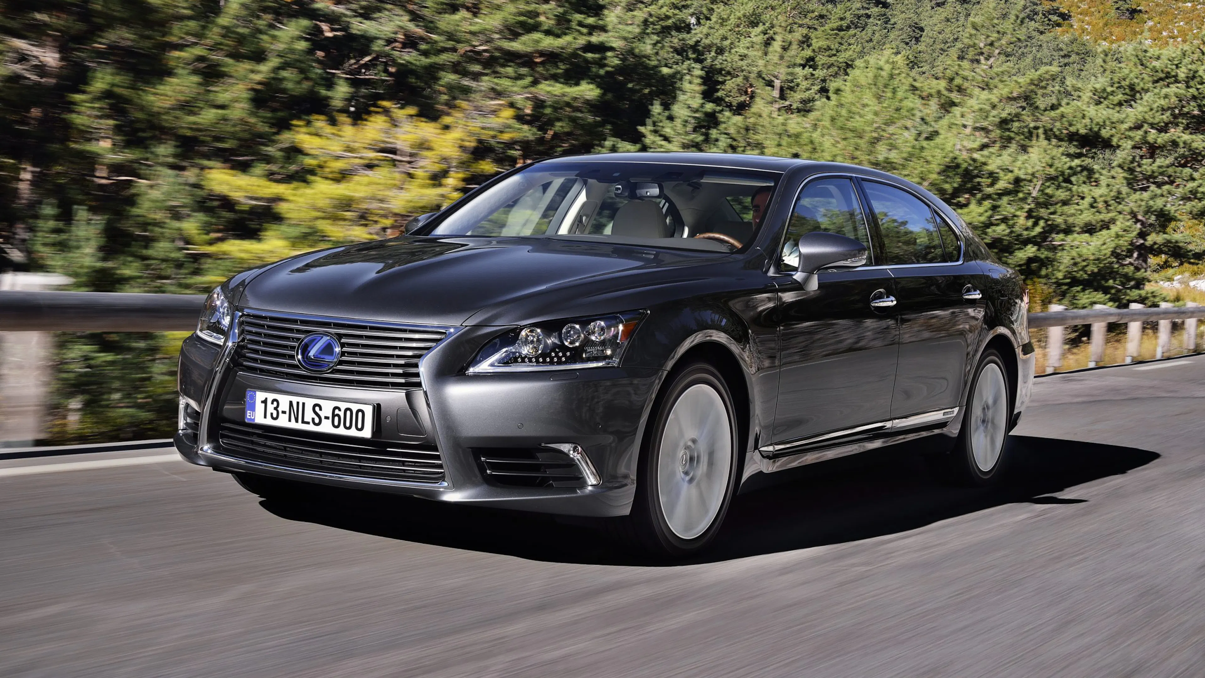 Ein schwarzer Lexus LS USF40 600H fährt auf einer Landstraße.