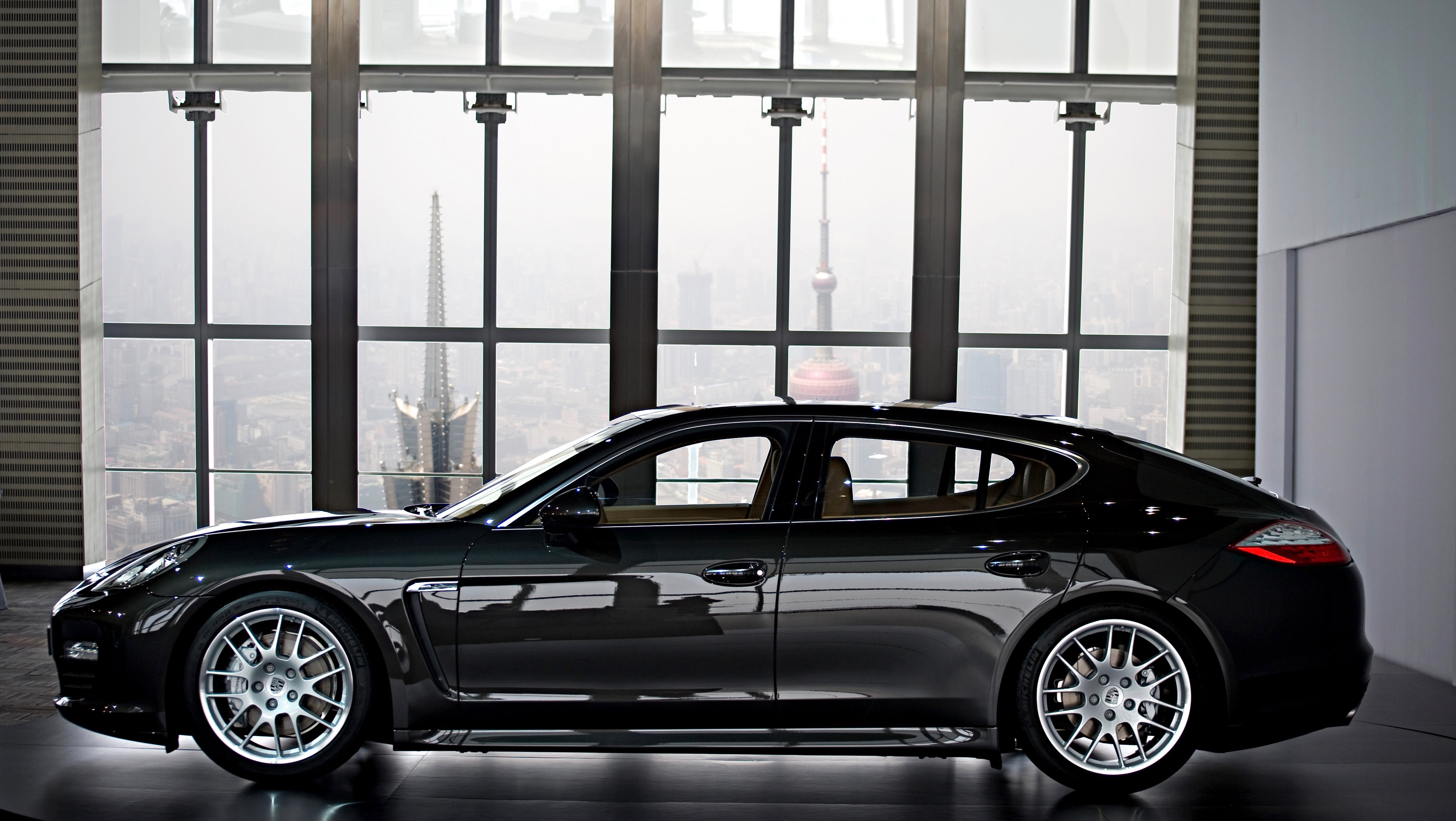 Ein schwarzer Porsche Panamera steht in einem Gebäude vor einer großen Glasfront.
