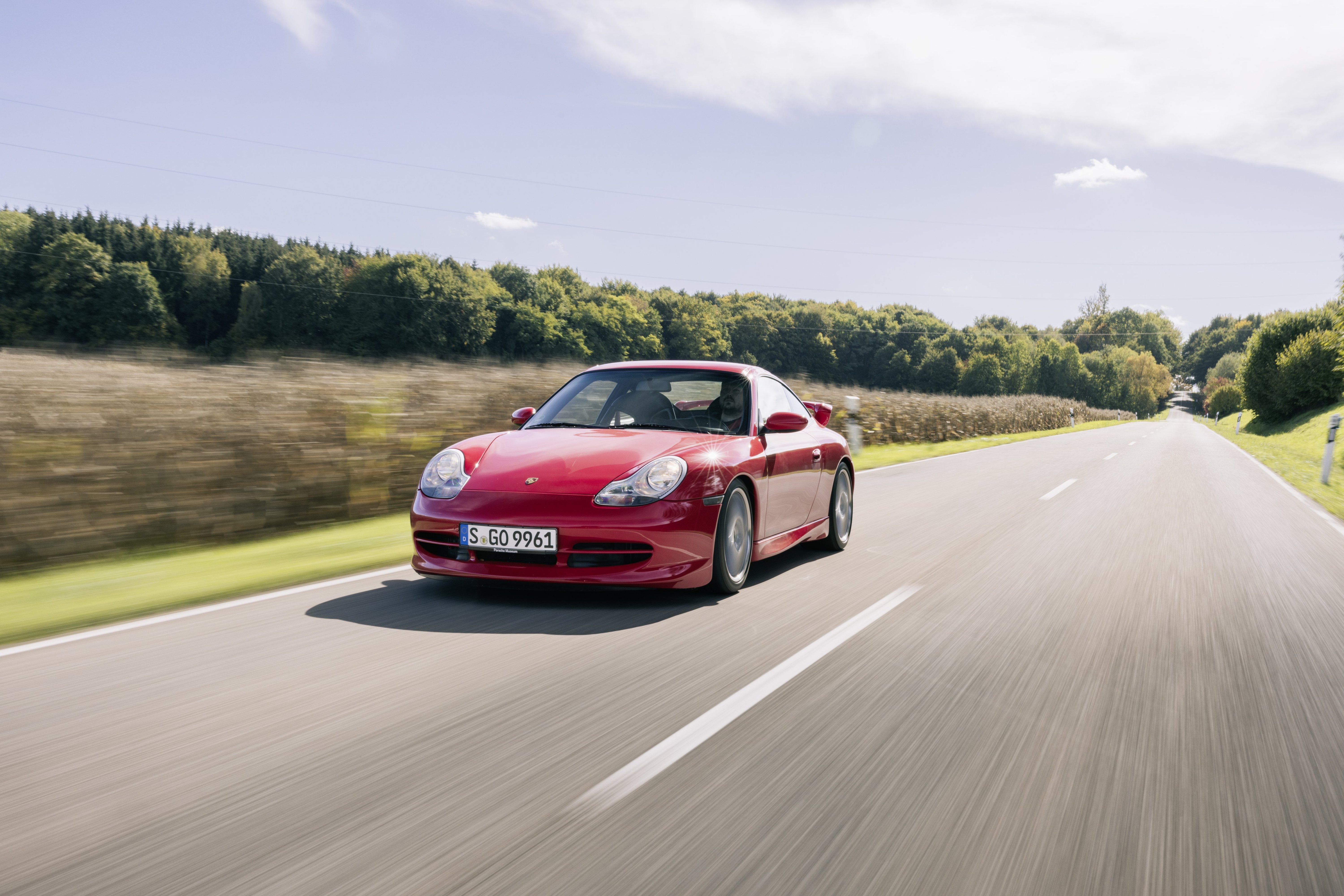 Ein roter Porsche 911 (996) fährt auf einer Landstraße.