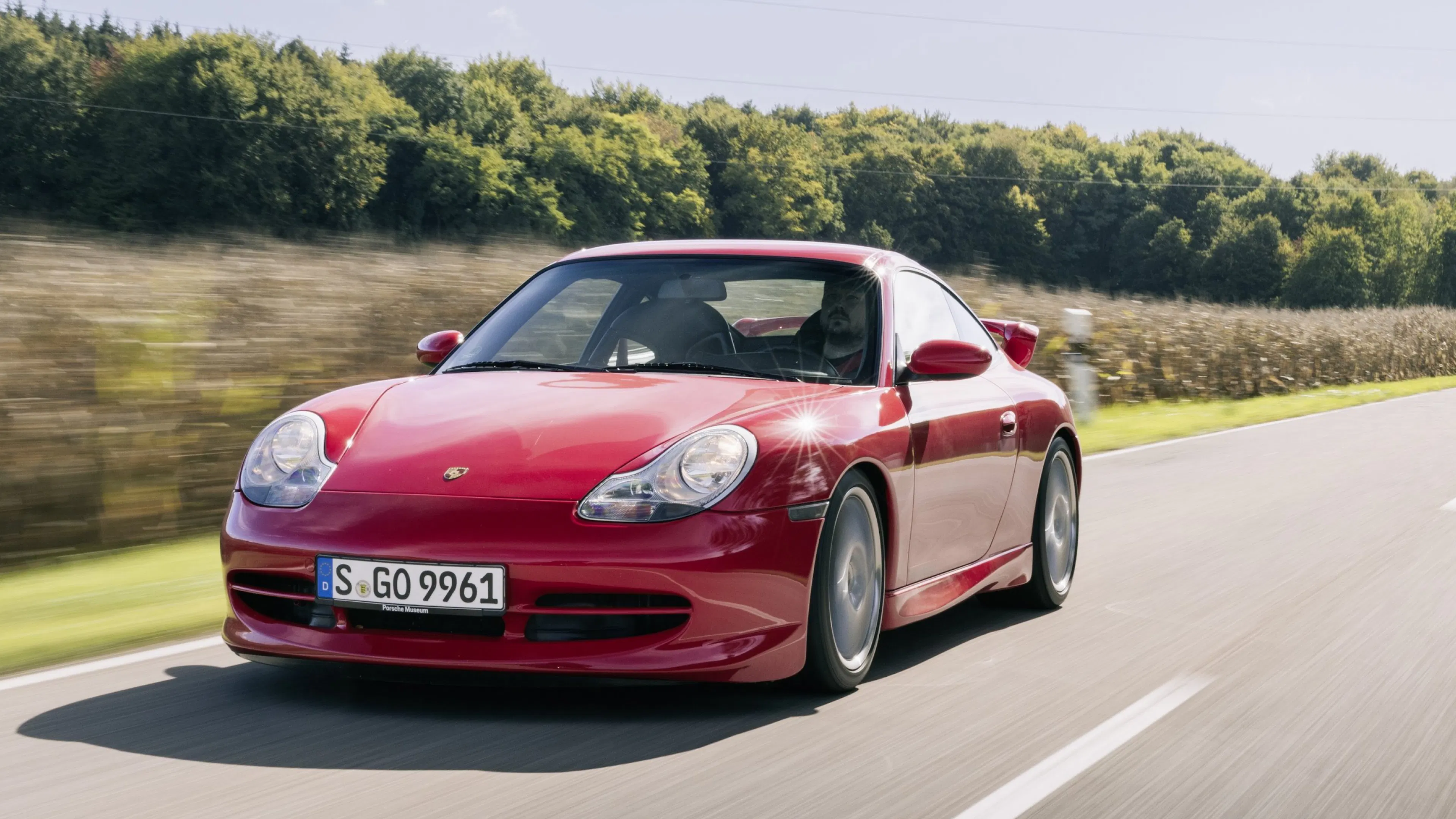 Ein roter Porsche 911 (996) fährt auf einer Landstraße.