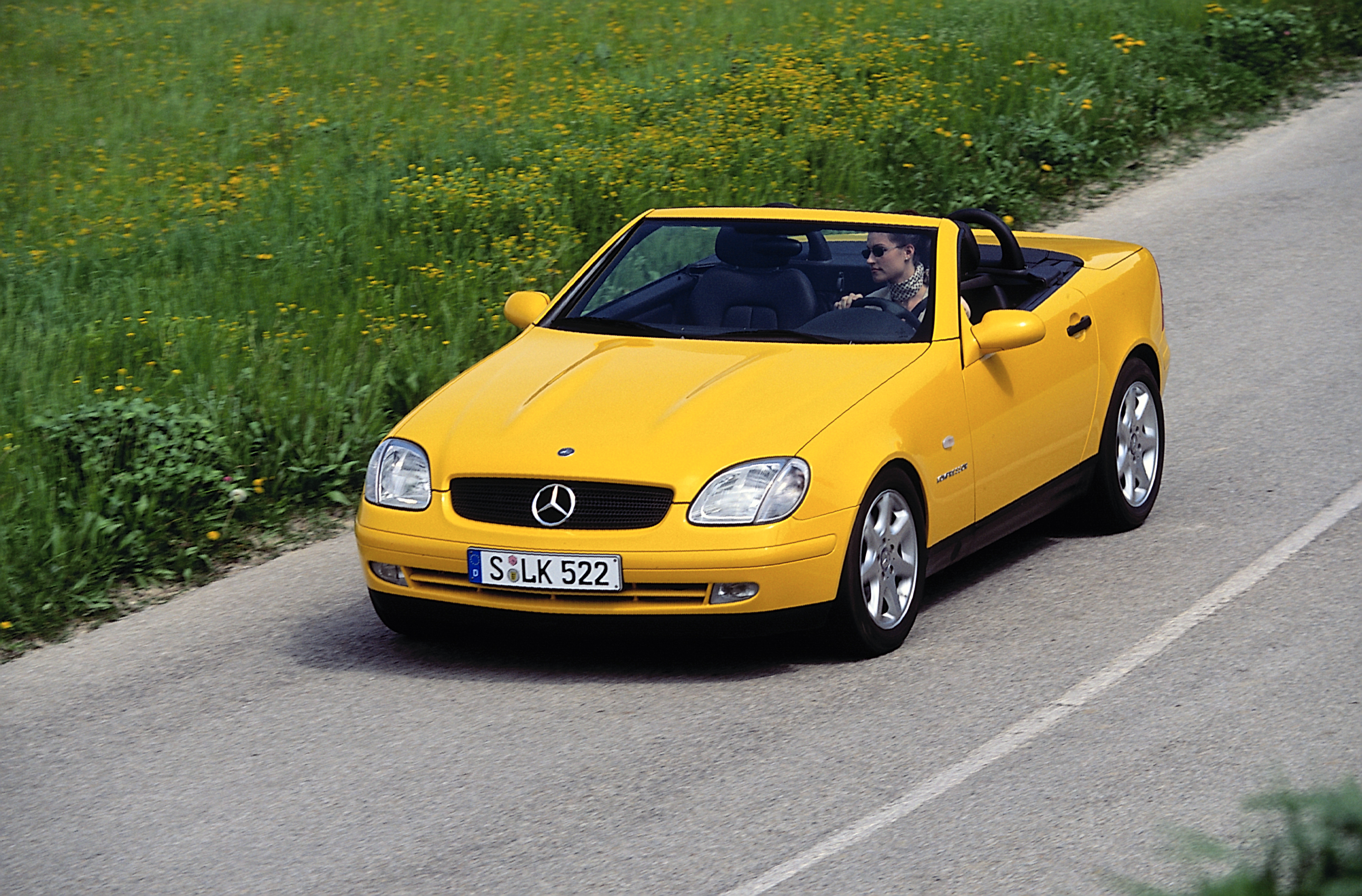 Ein gelber Mercedes-Benz SLK R170 fährt auf einer Landstraße.