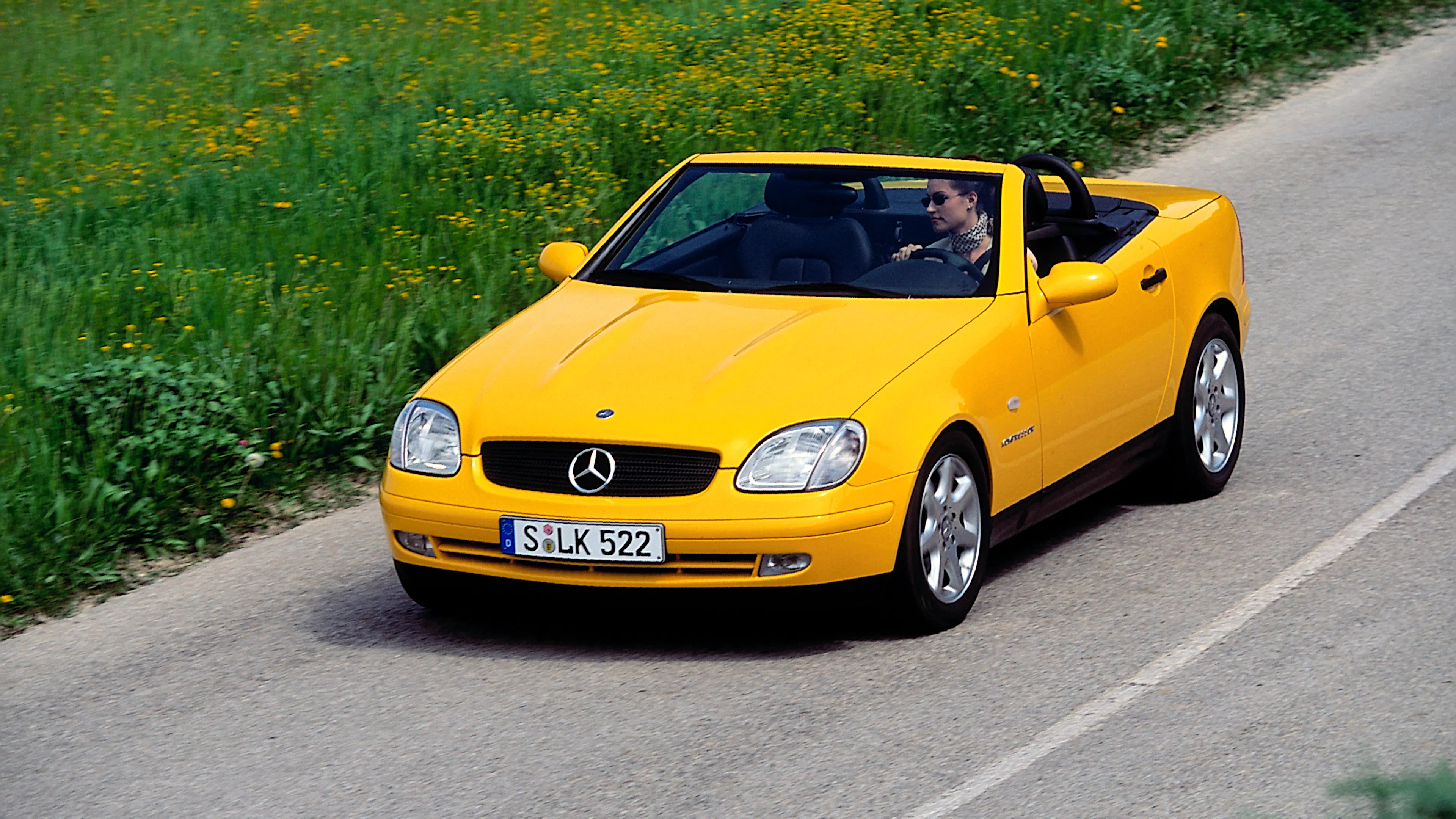 Ein gelber Mercedes-Benz SLK R170 fährt auf einer Landstraße.