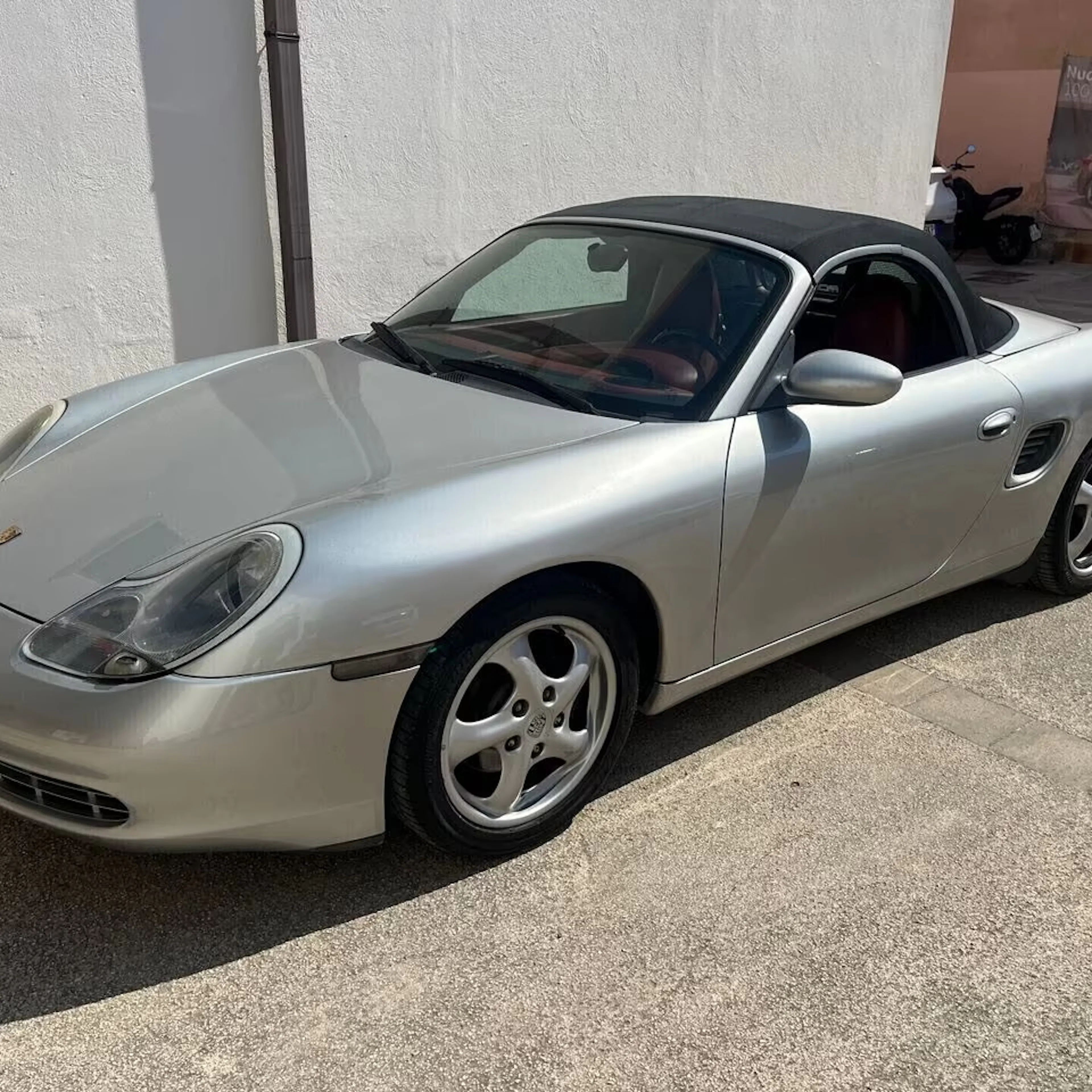 Ein silberner Porsche Boxszer steht auf einem Parkplatz.