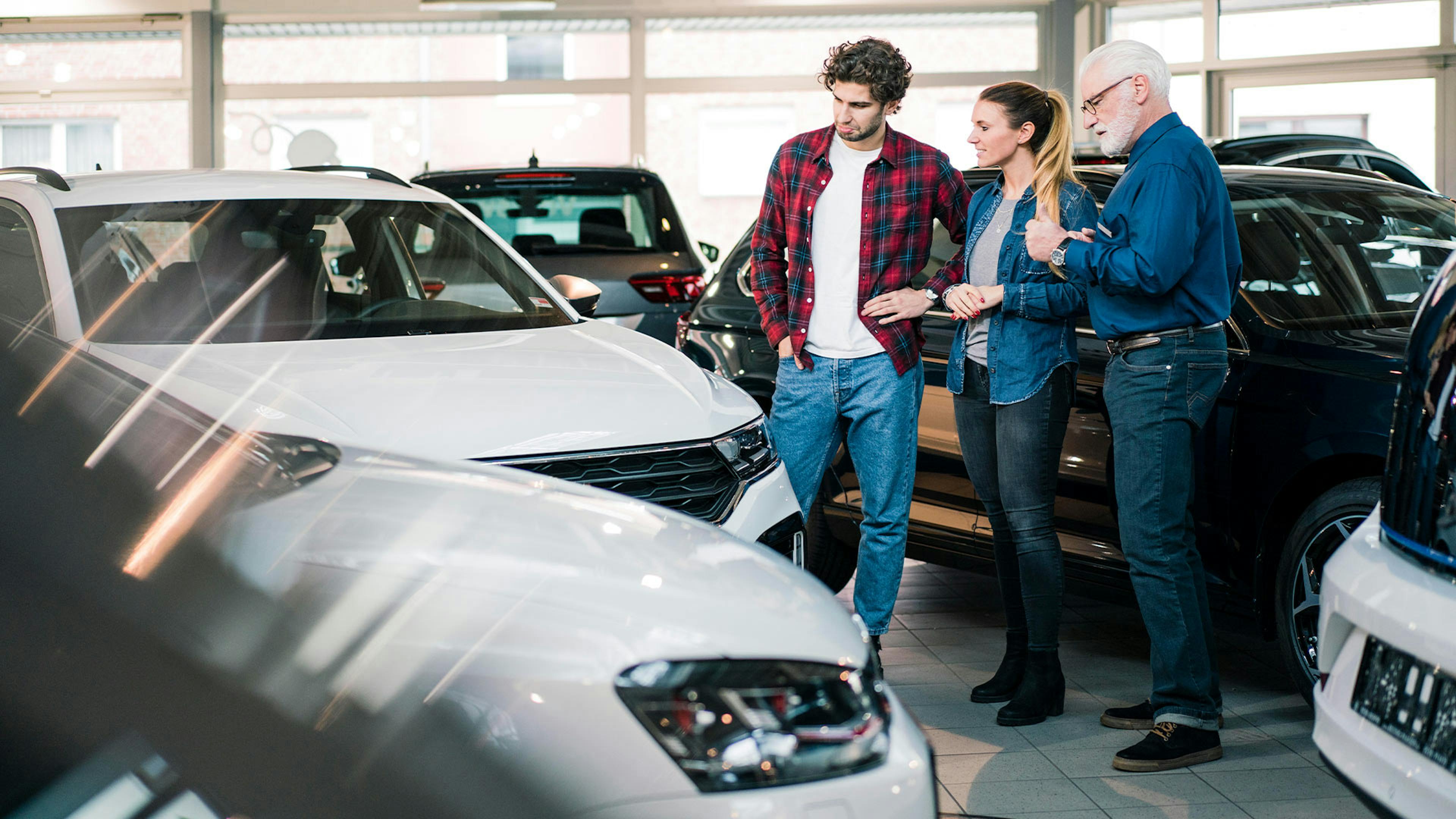Drei Personen bei einem Beratungsgespräch in einem Autohaus.