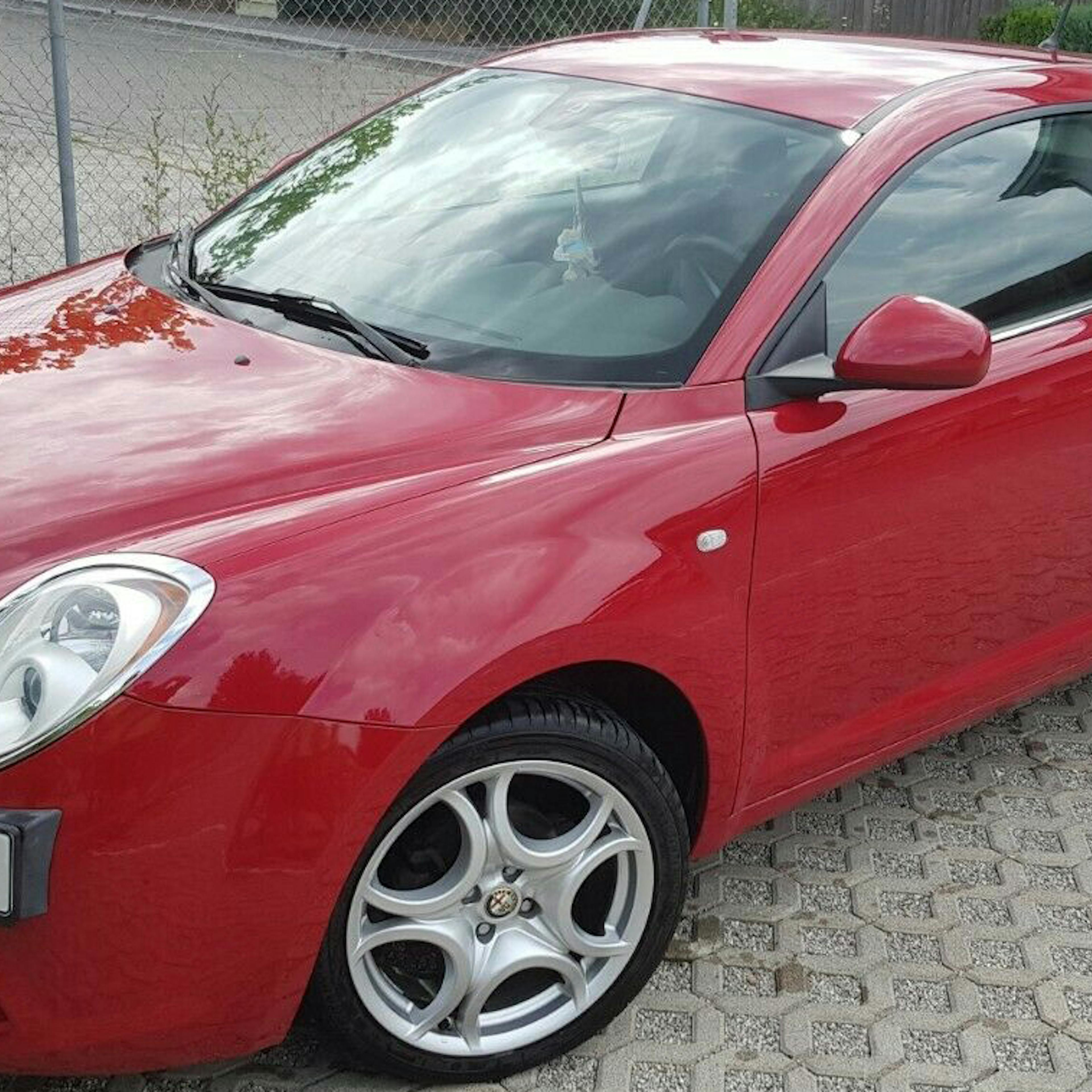 Ein roter Alfa Romeo Mito steht in einer Einfahrt.
