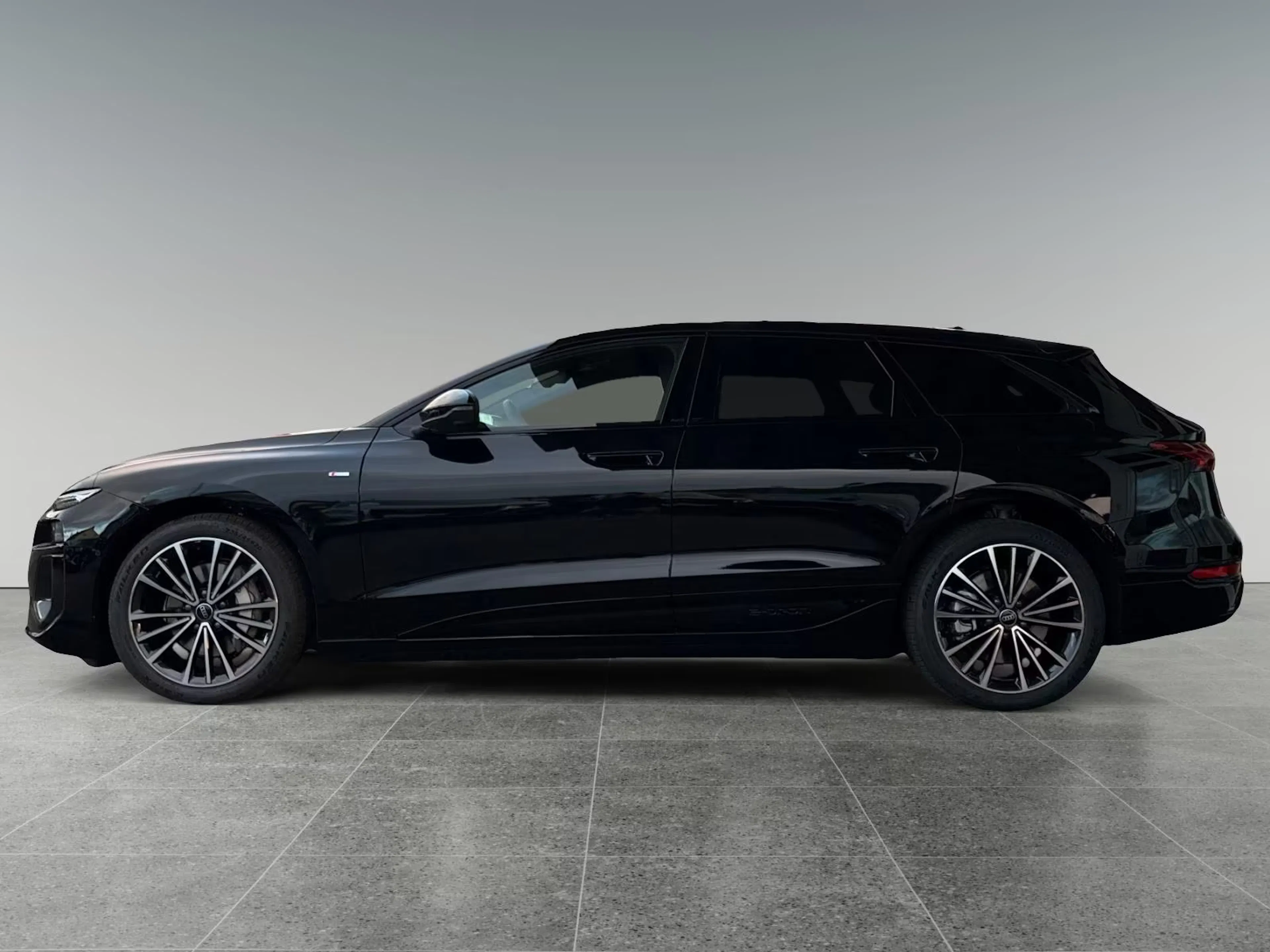 Ein schwarzer Audi A6 e-tron steht auf einem gefliestem Boden vor einer hellen Wand.