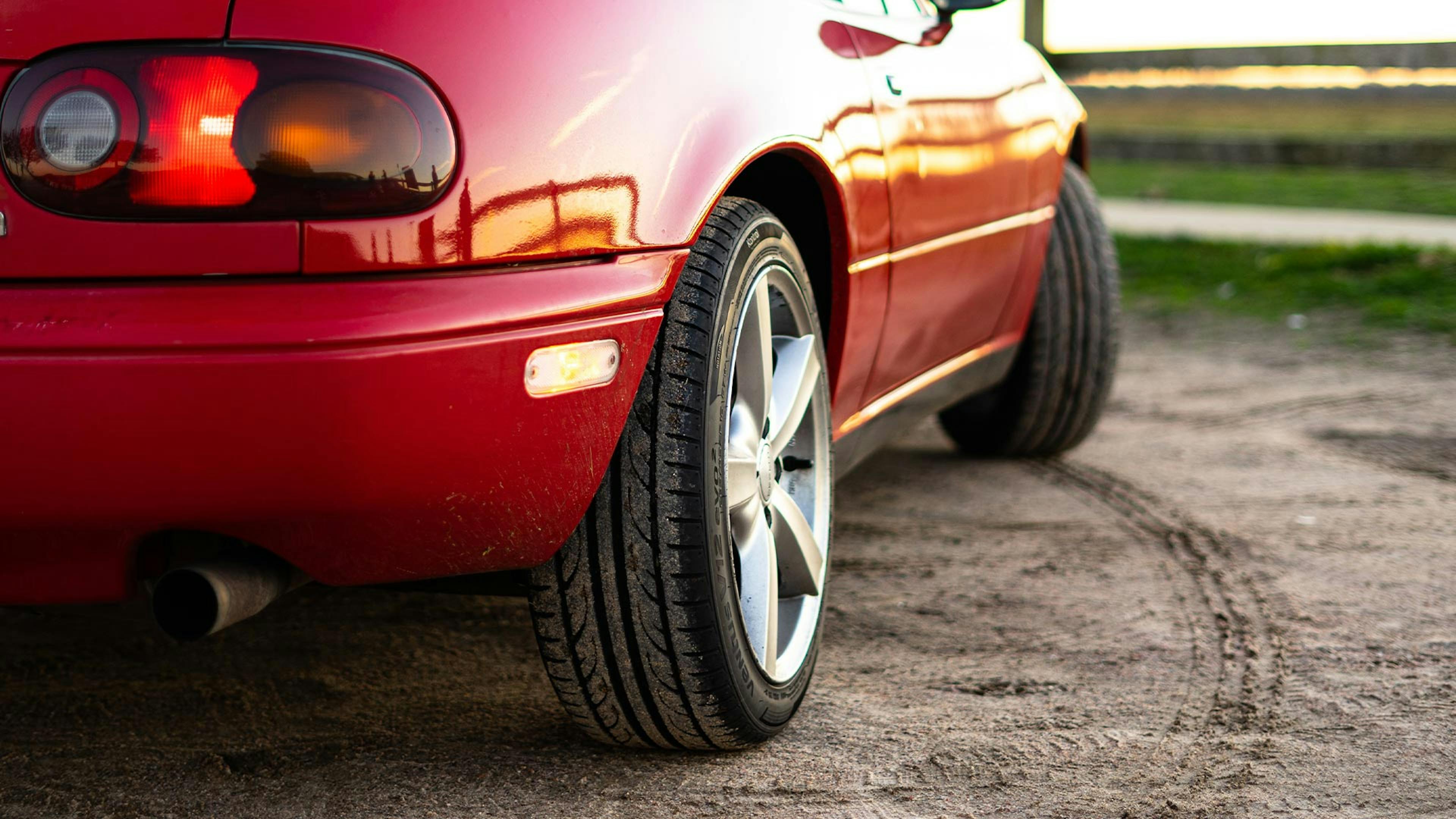 Blick auf das Heck eines roten Pkws, der zu einem Wendekreis ansetzt