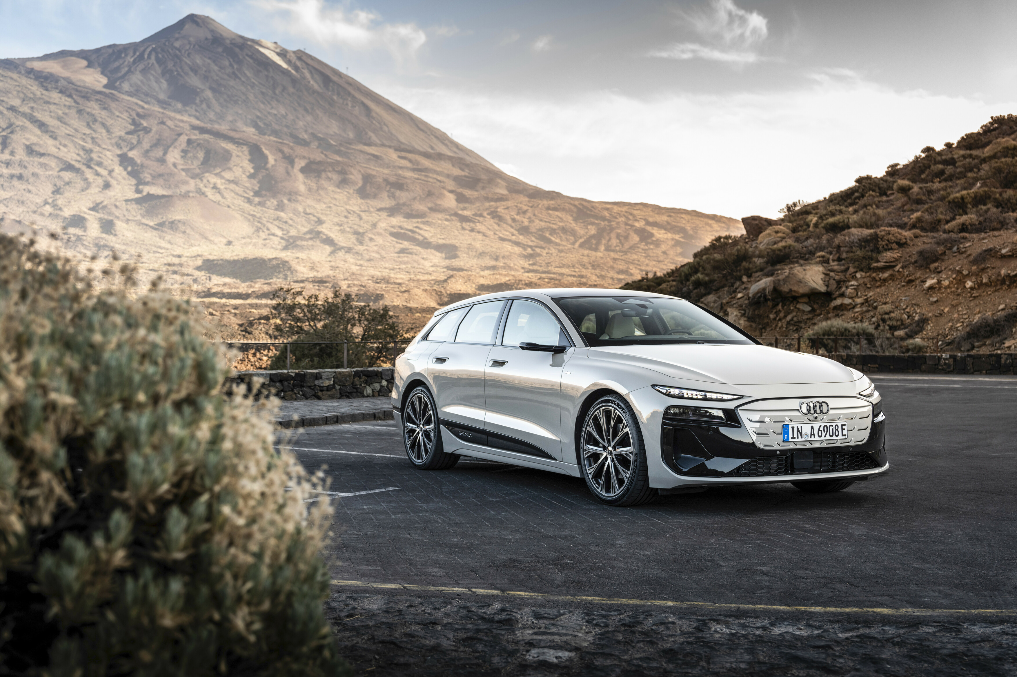 Ein hell lackierter Audi A6 Avant e-tron fährt auf einer Straße durch eine canyonartige Landschaft.