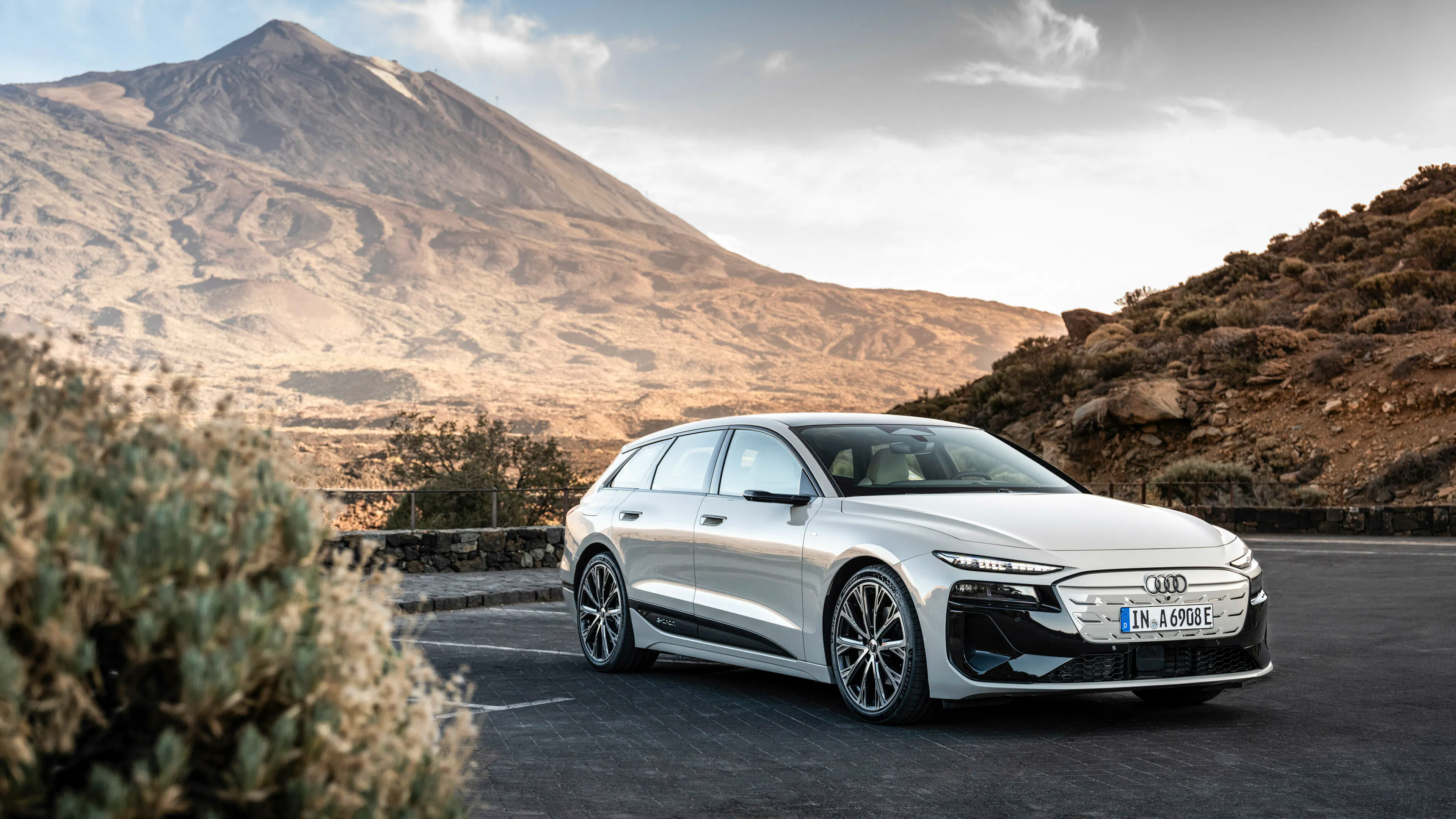 Ein hell lackierter Audi A6 Avant e-tron fährt auf einer Straße durch eine canyonartige Landschaft.