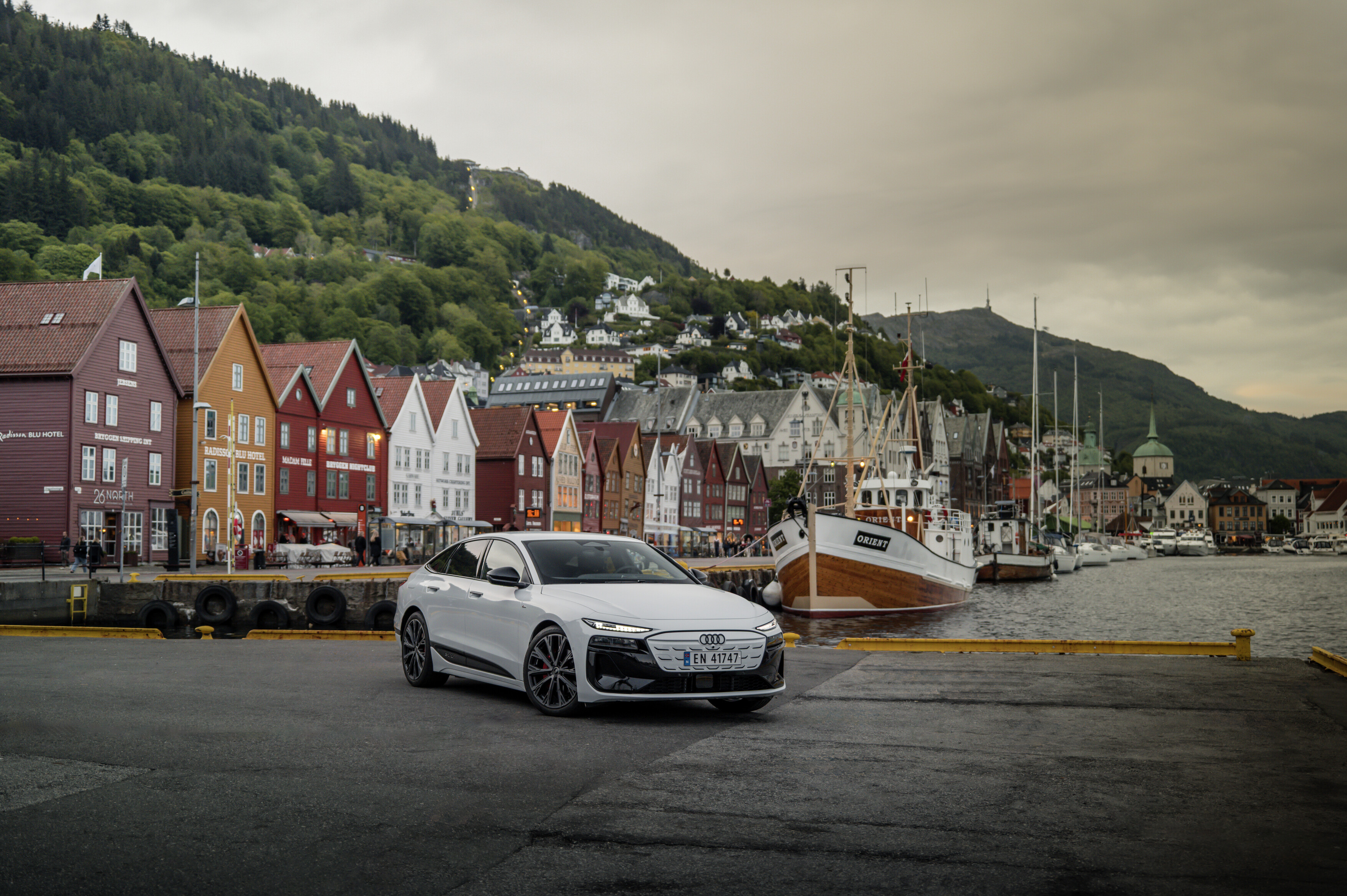 Ein Audi A6 Sportback e-tron steht vor skandinavisch anmutenden, schmalen Häusern mit Satteldächern.