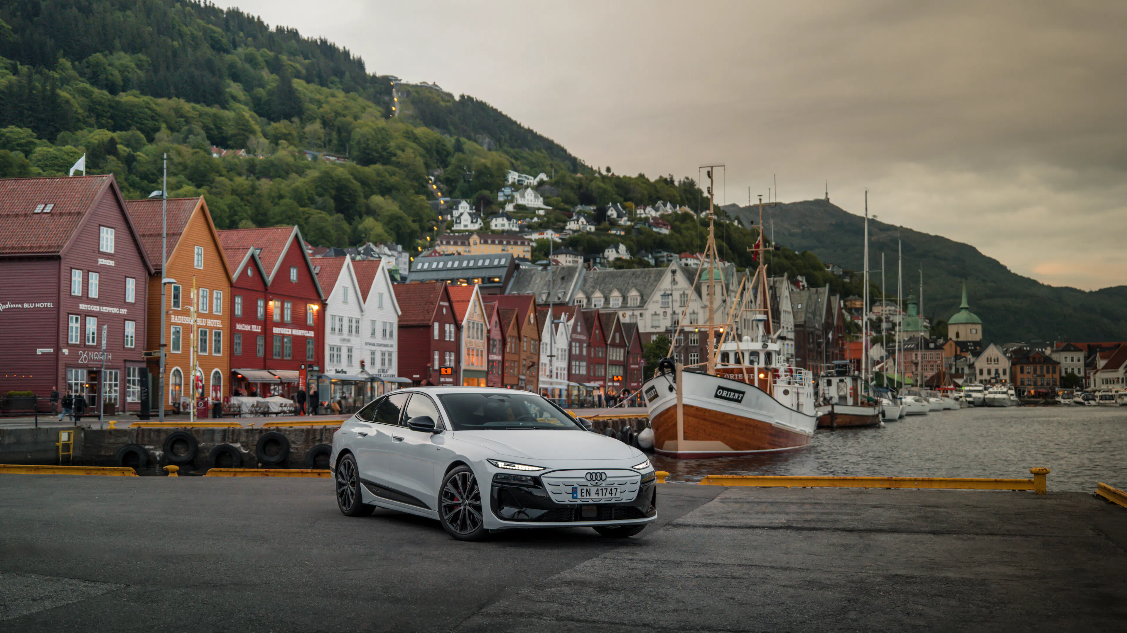Ein Audi A6 Sportback e-tron steht vor skandinavisch anmutenden, schmalen Häusern mit Satteldächern.