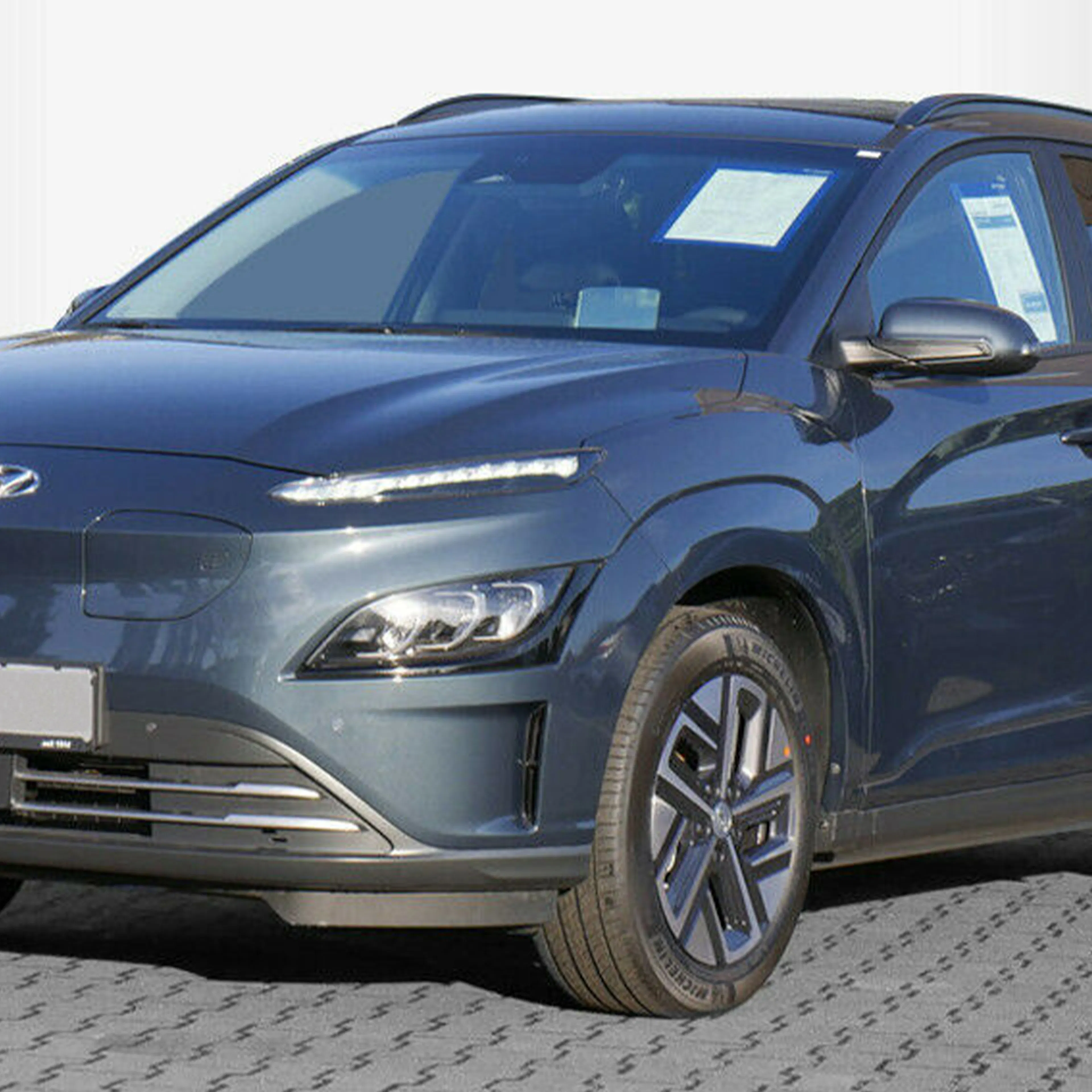 Dunkelblauer Hyundai Kona SUV, seitliche Frontansicht, auf hellem Hintergrund. Auto hat moderne LED-Scheinwerfer.